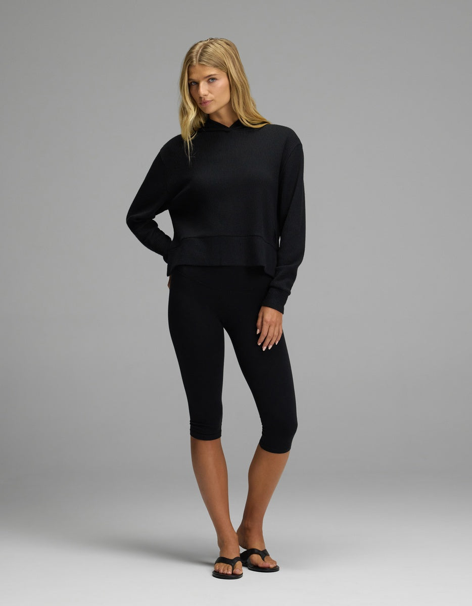 A woman wearing a black Women’s Blake Waffle Hoodie and black cropped leggings.