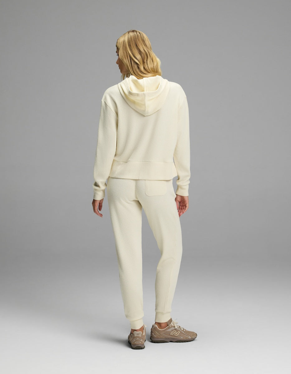 A person viewed from behind wearing a cream-colored Women’s Blake Waffle Hoodie & Jogger Set with sneakers.