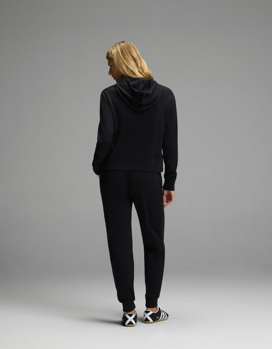 Back view of a person wearing a black Women’s Blake Waffle Hoodie & Jogger Set featuring a waffle-knit hooded long-sleeve shirt and matching joggers.