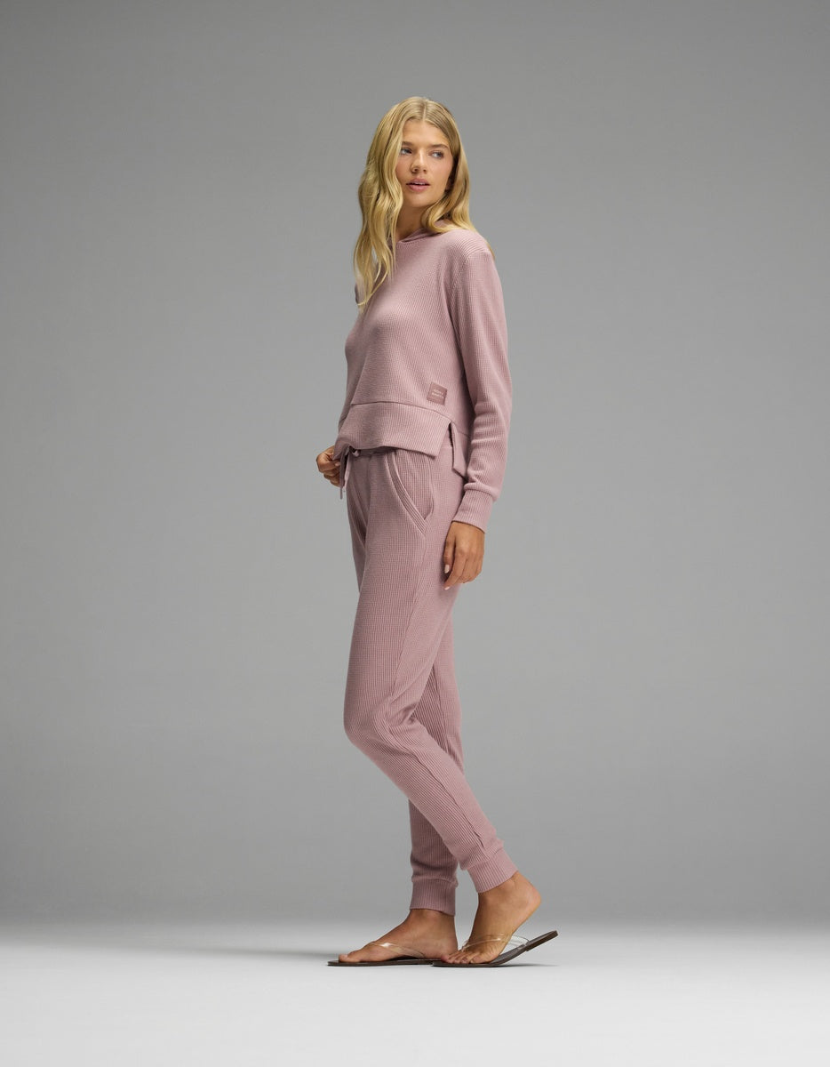 A person wearing a dusty pink Women’s Blake Waffle Hoodie & Jogger Set in a waffle-knit fabric.