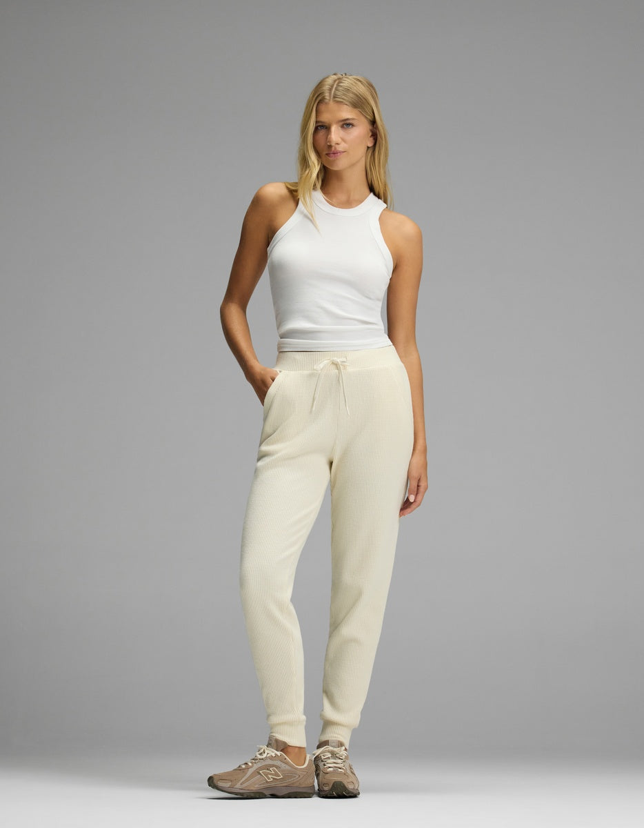 Woman wearing a white ribbed tank top and cream-colored Women’s Blake Waffle Jogger with a drawstring waist.