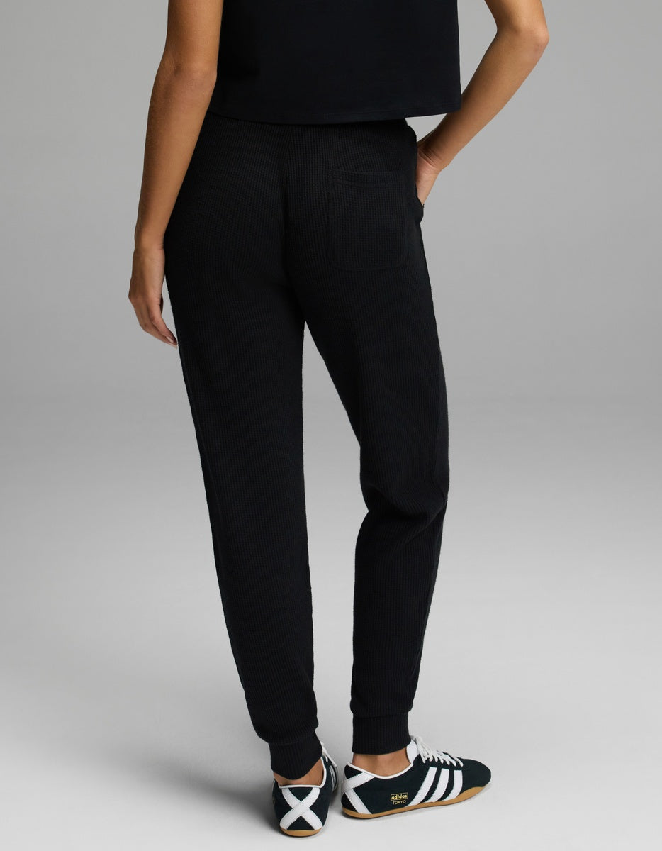 Back view of a person wearing black Women’s Blake Waffle Jogger pants with ribbed cuffs and sneakers.