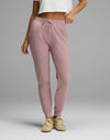 A person wearing mauve Women’s Blake Waffle Jogger pants with a drawstring waist and ribbed cuffs, paired with tan sneakers.|Color:Viola