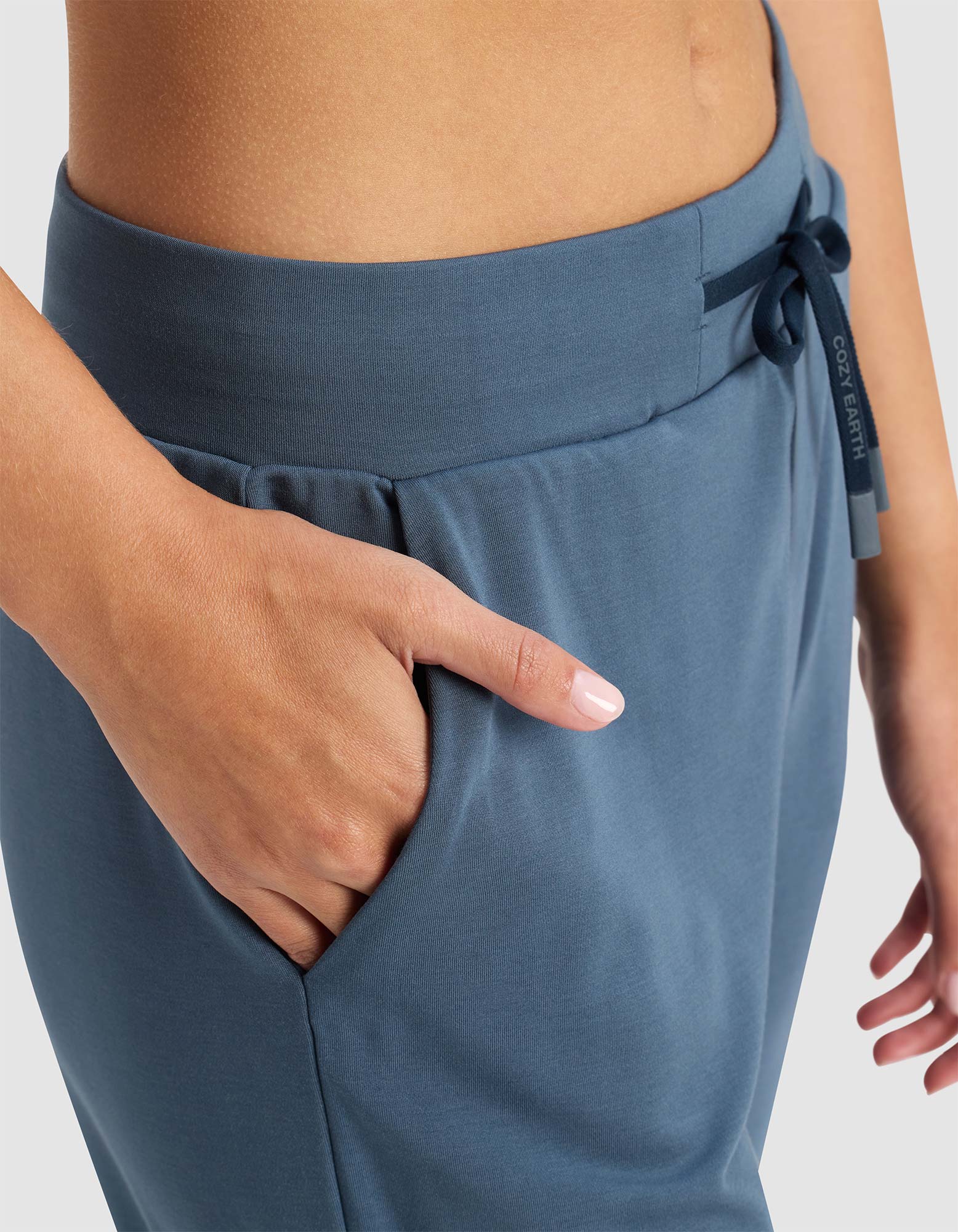 A close-up of a person wearing Cozy Earth's Women's Brushed Bamboo Jogger Pant, featuring a drawstring waist, right hand in the pocket, and showcasing the pants' soft, smooth texture.