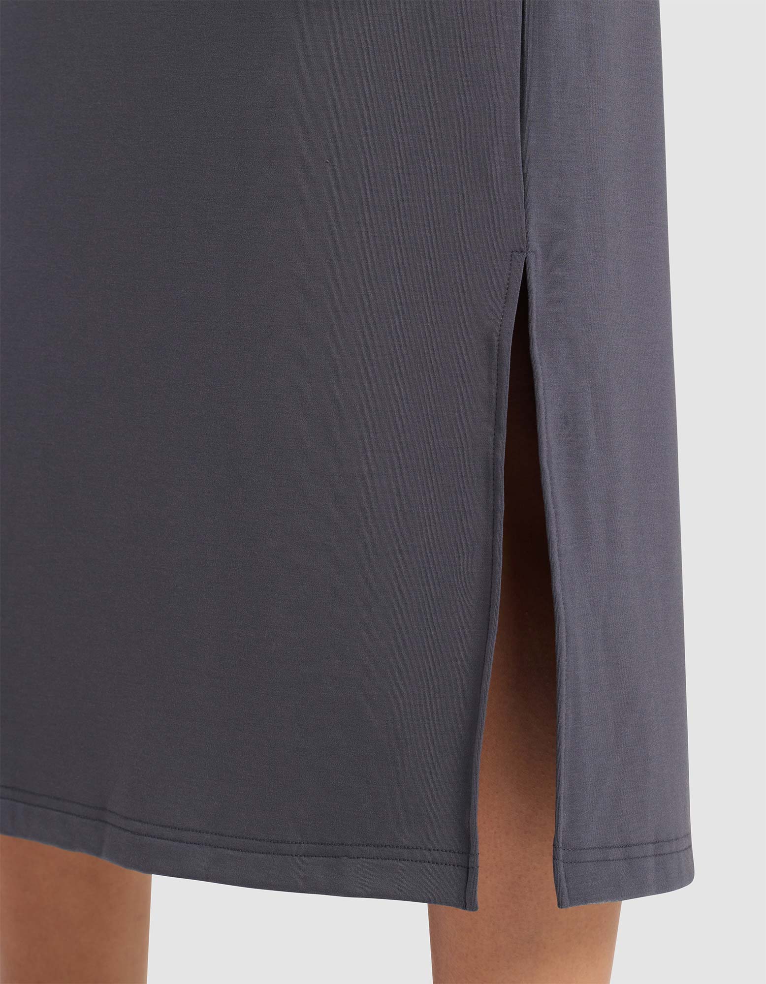 Close-up of the lower part of the Cozy Earth Women's Brushed Bamboo Midi Dress in dark gray, showing a side slit that reveals part of the leg. The smooth, slightly stretchy fabric adds to its comfort and elegance.
