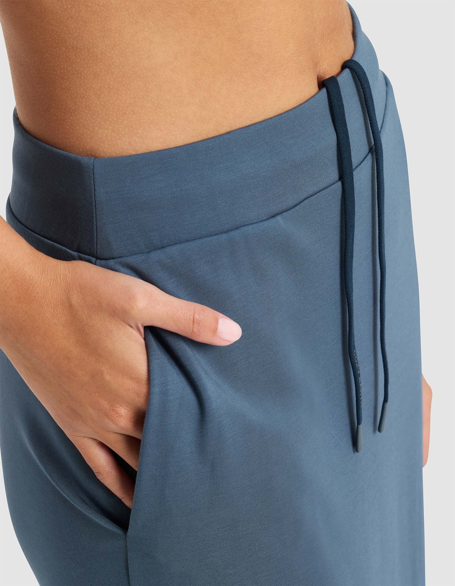 Close-up of a person’s hand in the pocket of the Cozy Earth Women’s Brushed Bamboo Midi Skirt, showing part of the waist and hip against a light background.