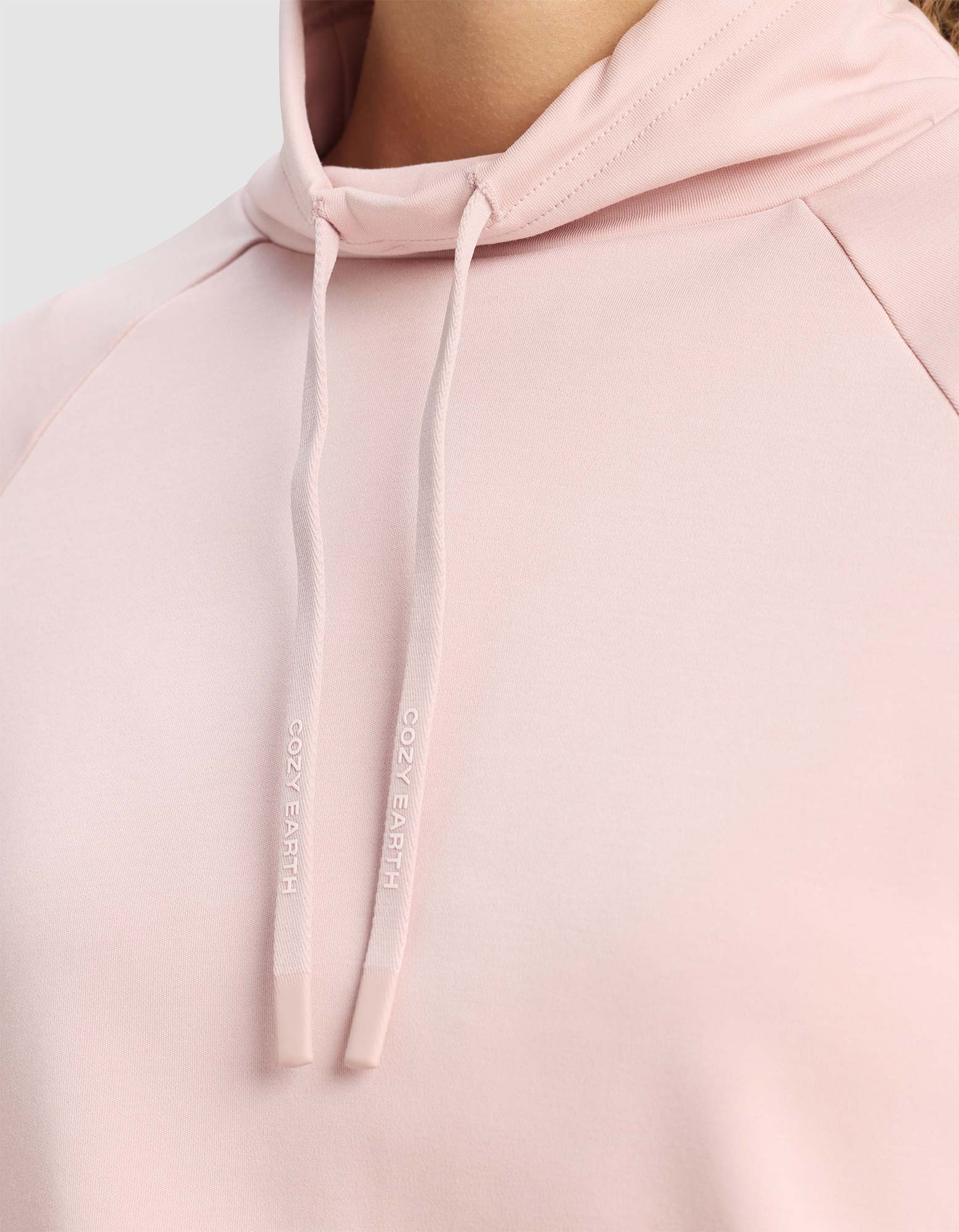 Close-up of Cozy Earth’s Women's Brushed Bamboo Mock Neck in light pink, with branded "COZY EARTH" drawstrings. The soft, smooth fabric stands out against a neutral gray background.