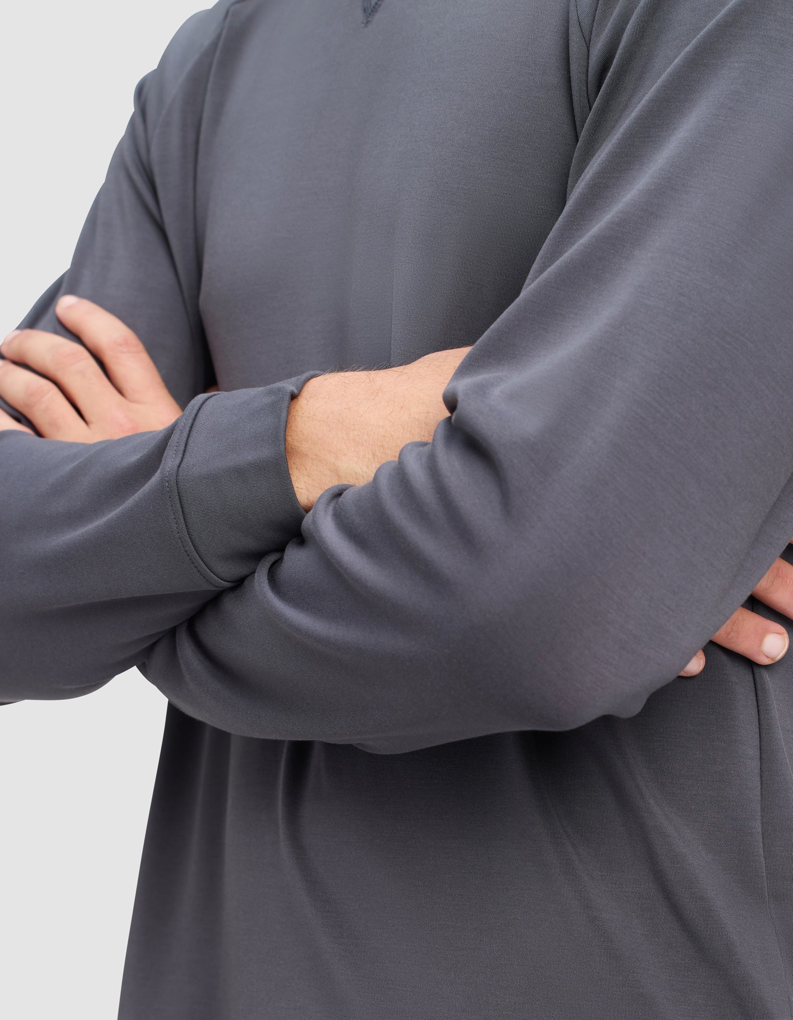 A person wears the Cozy Earth Men's Brushed Bamboo Pullover Crew in dark gray, standing with arms crossed against a neutral background. Only the torso and arms are shown.