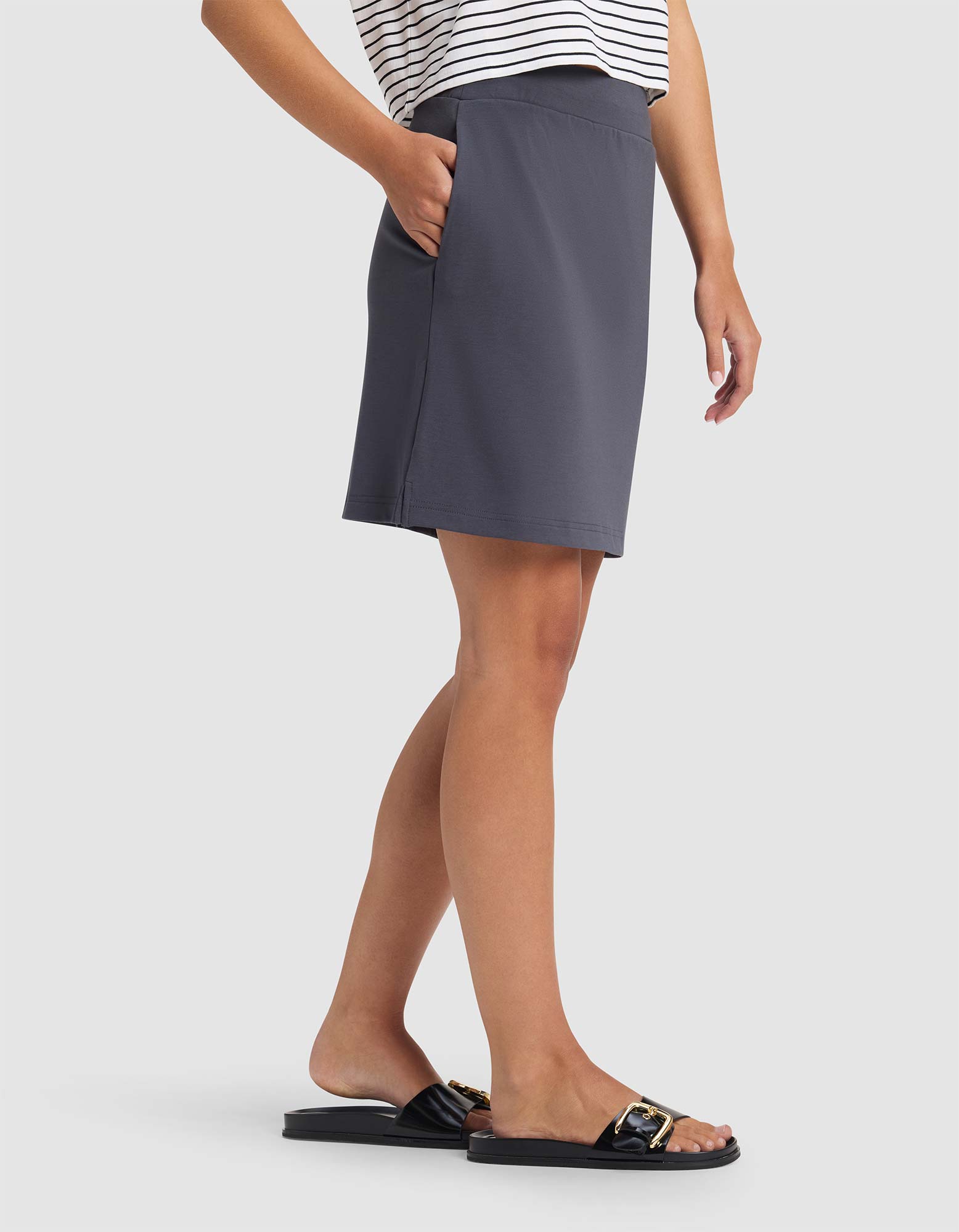 Person wearing a gray skirt and black sandals on a white background 