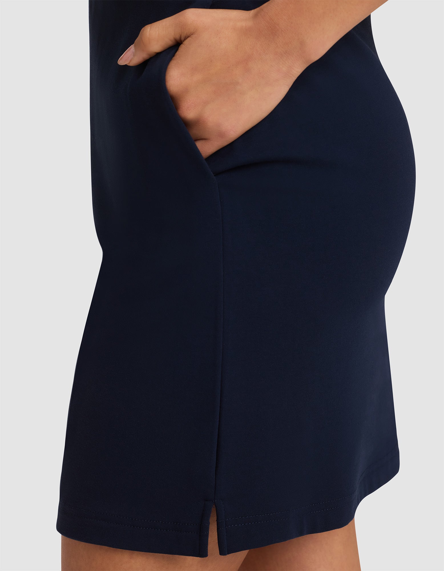 A close-up shows a person wearing the Cozy Earth Women's Brushed Bamboo Skirt in navy blue with a small front slit, their hand resting inside the skirt pocket. 