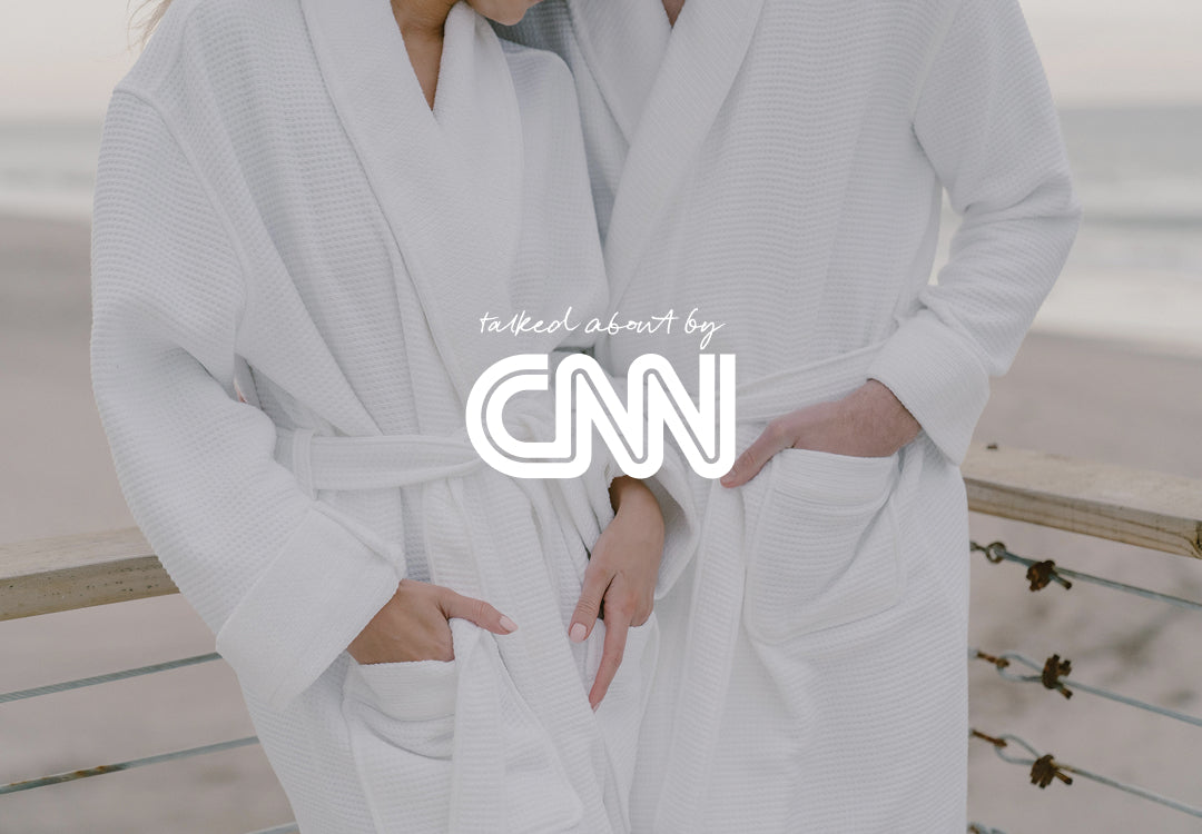 A man and women with matching robes with the beach in the background.  A CNN logo on top.