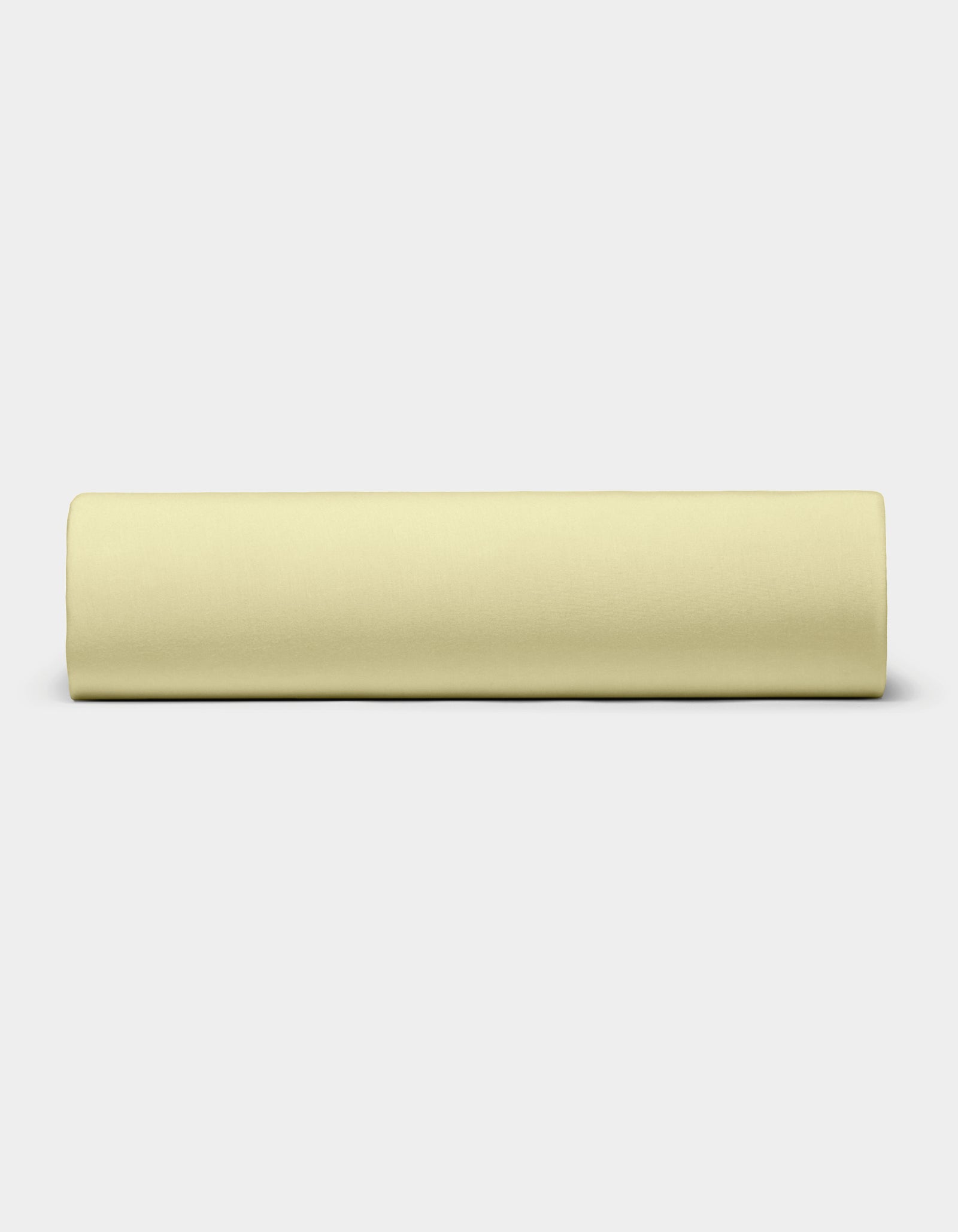 The Bamboo Jersey Sheet Set by Cozy Earth, in pale yellow, is neatly rolled and placed horizontally on a plain white background.