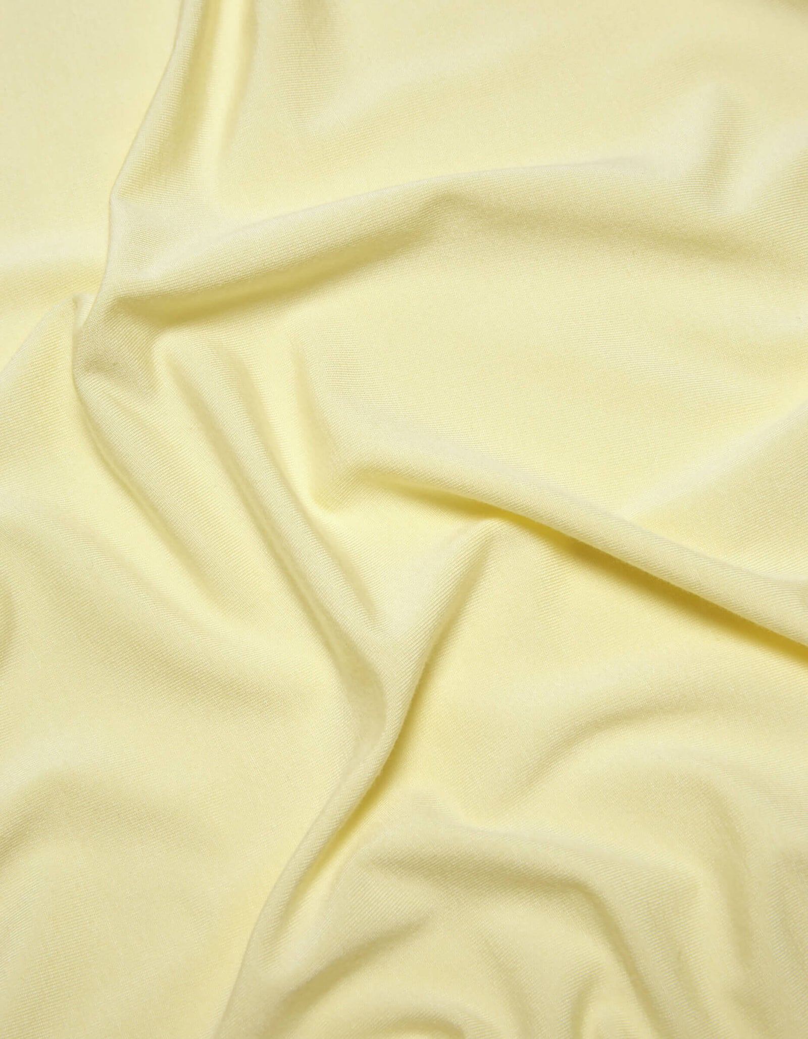 A close-up of Cozy Earth's Bamboo Jersey Sheet Set in pale yellow, featuring soft folds and gentle wrinkles for a smooth, slightly textured look.