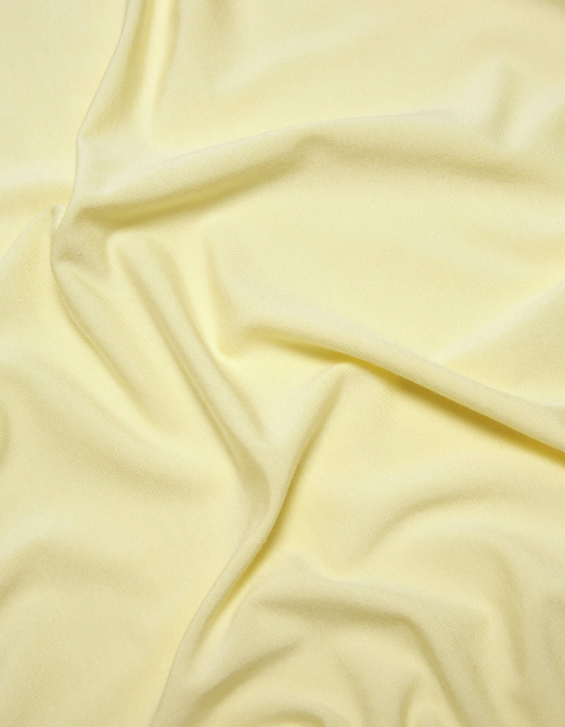A close-up of Cozy Earth's Bamboo Jersey Sheet Set in pale yellow, featuring soft folds and gentle wrinkles for a smooth, slightly textured look.