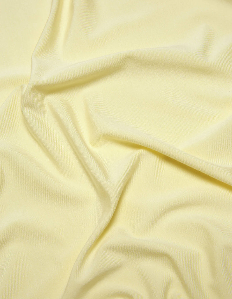 A close-up of Cozy Earth's Bamboo Jersey Sheet Set in pale yellow, featuring soft folds and gentle wrinkles for a smooth, slightly textured look.