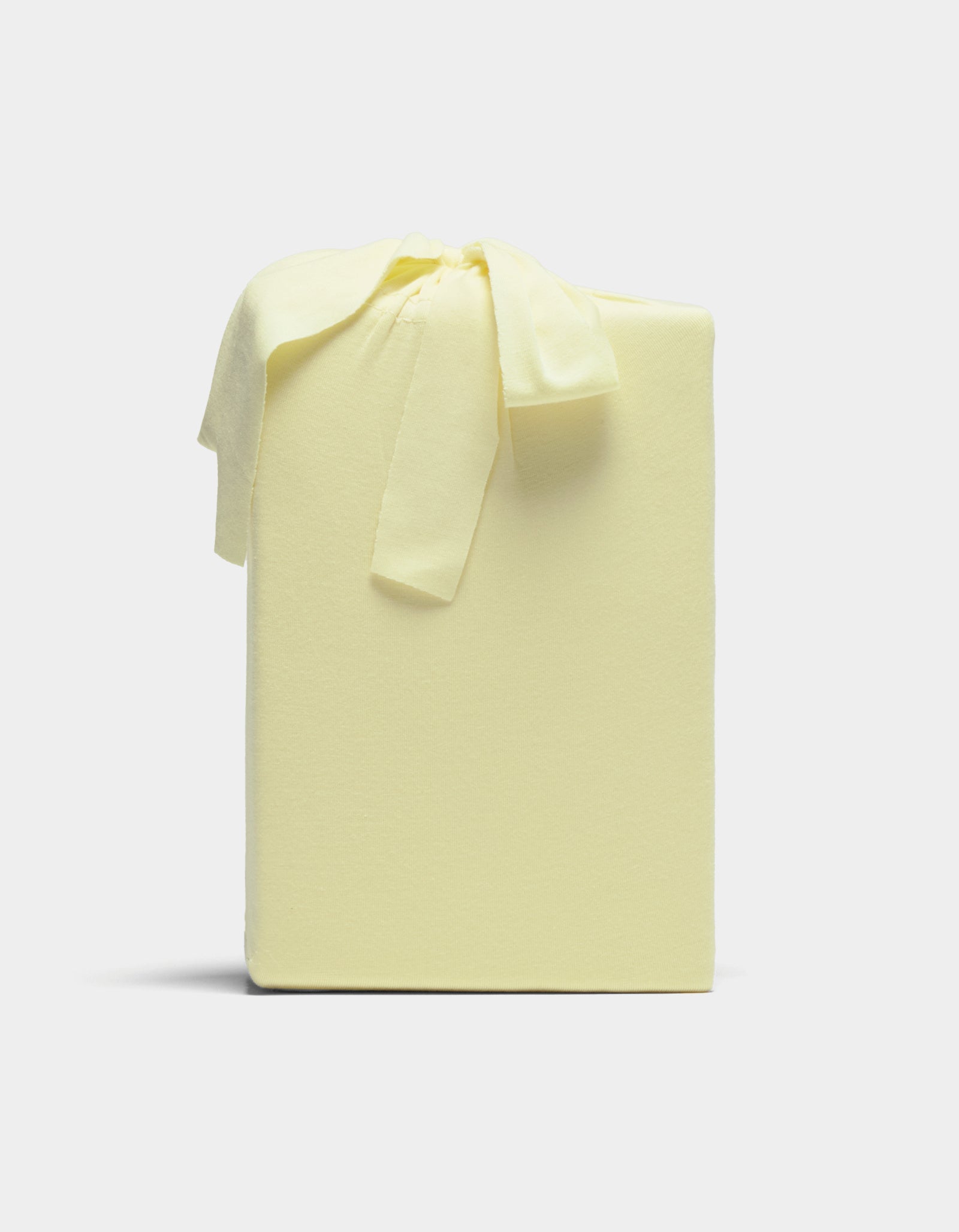 A Cozy Earth Bamboo Jersey Sheet Set, neatly wrapped in pale yellow fabric with a matching bow, is displayed against a plain light background.