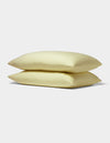 Two Bamboo Jersey Pillowcases from Cozy Earth, displayed in soft pale yellow and stacked neatly against a plain white background.|Color:Meringue