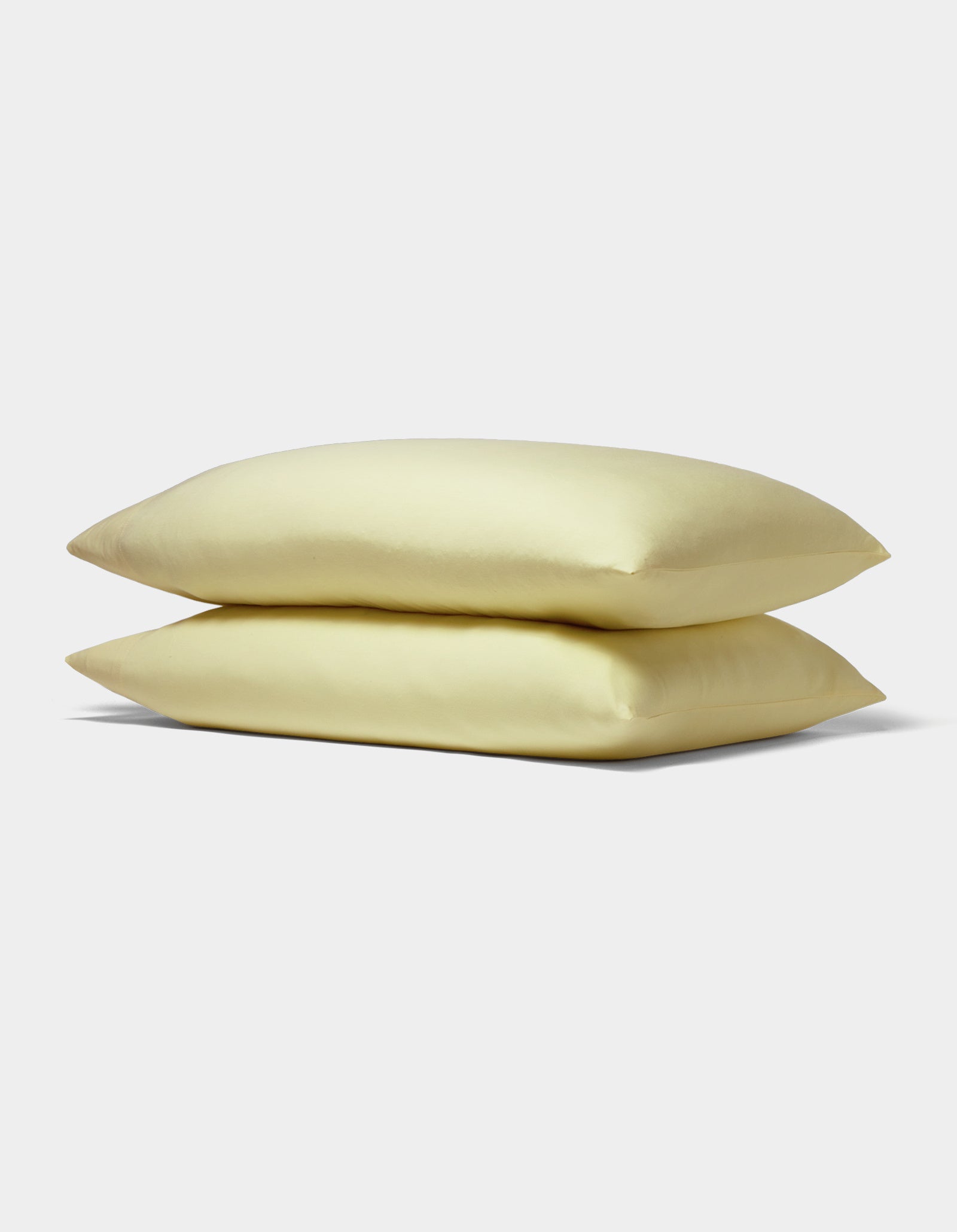Two Bamboo Jersey Pillowcases from Cozy Earth, displayed in soft pale yellow and stacked neatly against a plain white background.