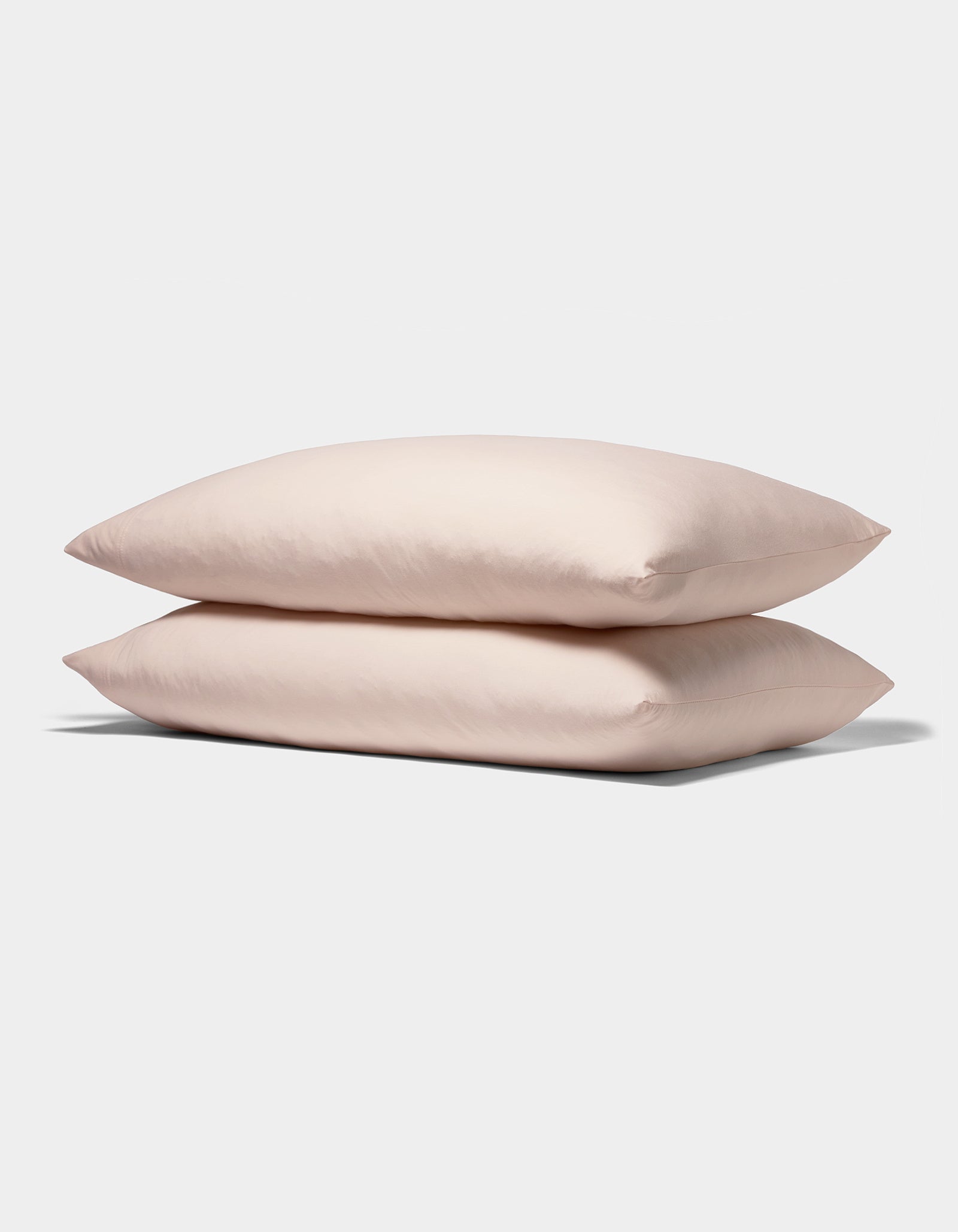 Two Bamboo Jersey Pillowcases from Cozy Earth, in soft light pink, are stacked neatly against a plain white background.