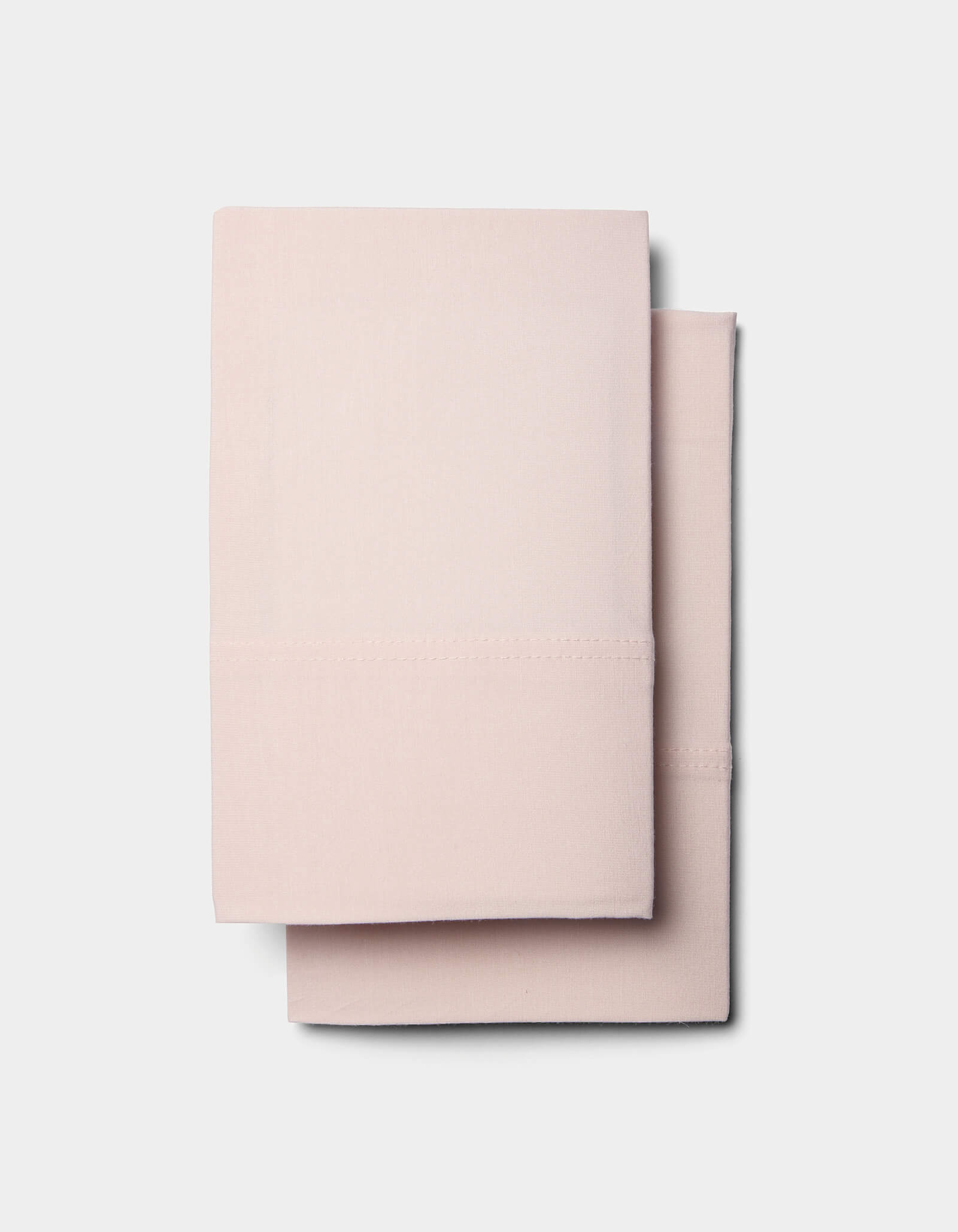 Two neatly folded Cozy Earth Bamboo Jersey Sheet Sets in light pink are stacked on top of each other against a plain white background.