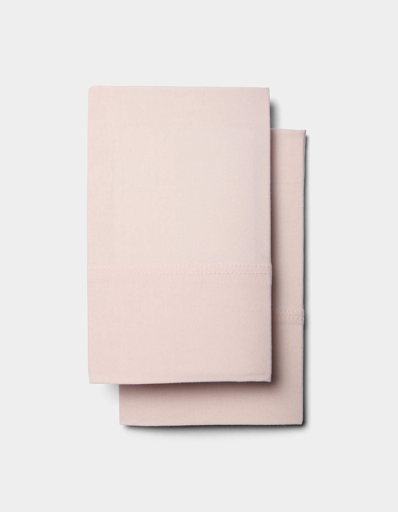 Two neatly folded Cozy Earth Bamboo Jersey Sheet Sets in light pink are stacked on top of each other against a plain white background.