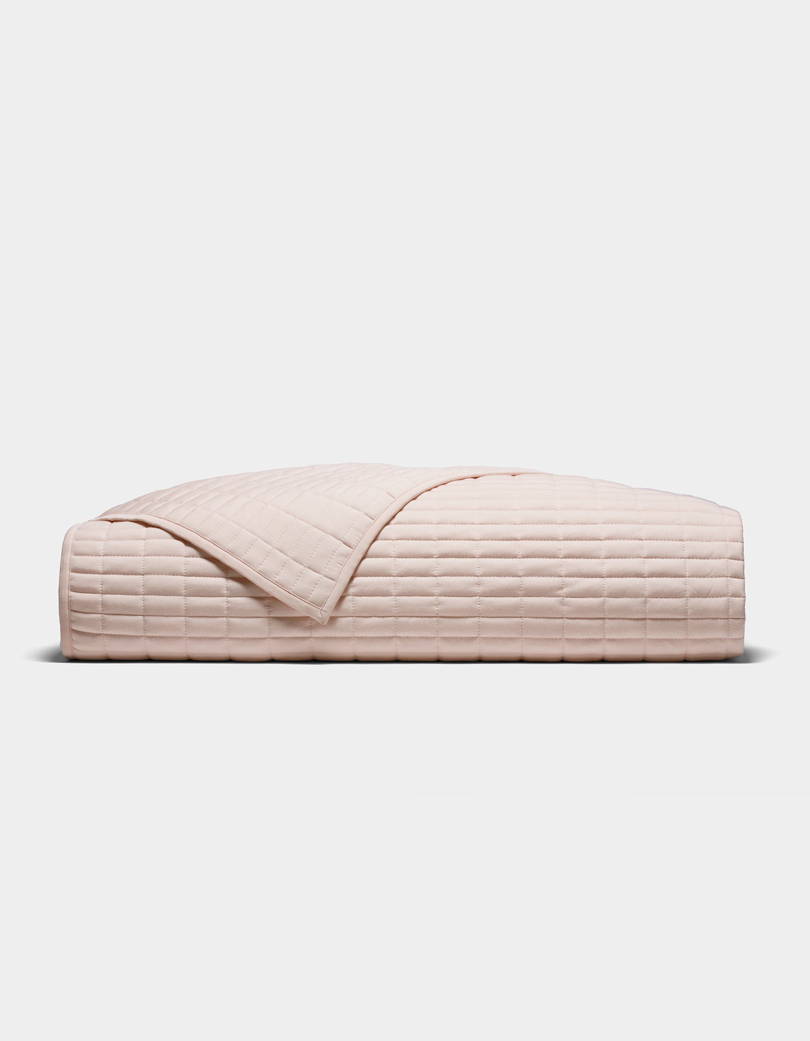 The Cozy Earth Bamboo Jersey Quilt, shown folded in blush-pink with a quilted grid pattern, is displayed against a plain white background.