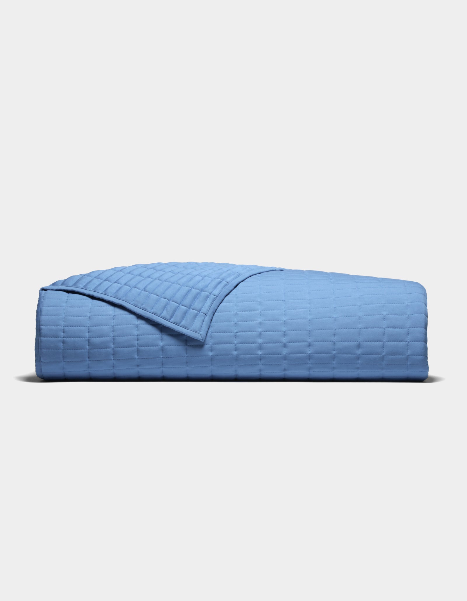The Cozy Earth Bamboo Jersey Quilt, featuring a textured grid-like pattern in light blue, is neatly folded and displayed against a plain white background.