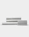 A neatly stacked set of Cozy Earth Bamboo Bedding Core Bundle sheets, featuring white fabric with thin grey stripes, displayed against a plain light background.|Color:Classic Stripe in Dew