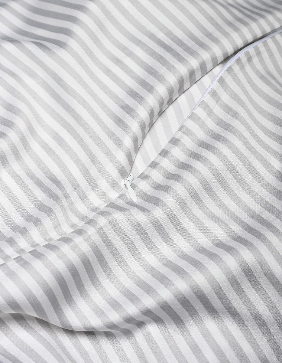 A close-up of the Cozy Earth Bamboo Duvet Cover in white and gray stripes, featuring a partially unzipped zipper that reveals its smooth, shiny texture and soft folds.