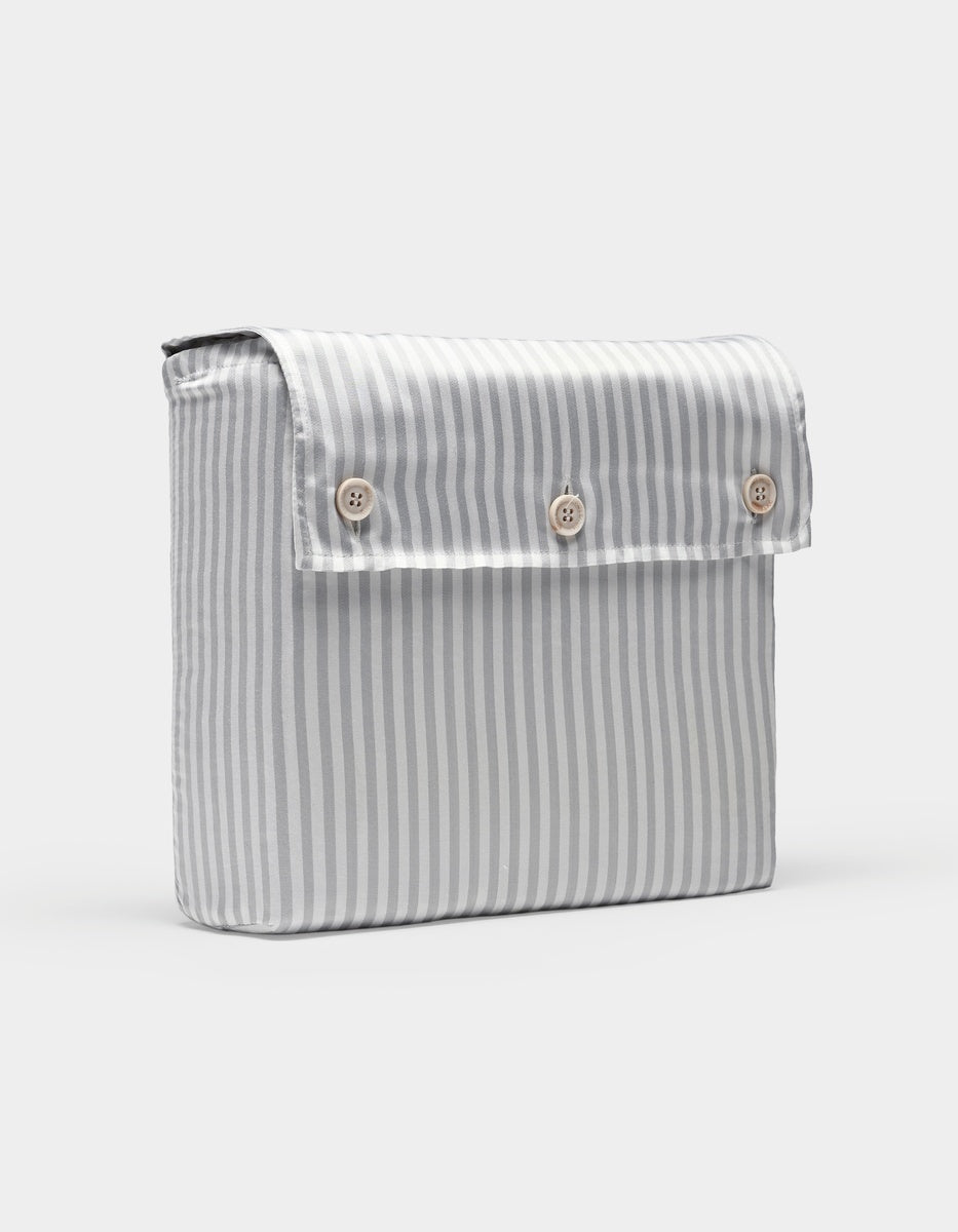 A Bamboo Sheet Set by Cozy Earth featuring vertical gray and white stripes and a rectangular fabric pouch with a flap secured by three light-colored buttons on the front.