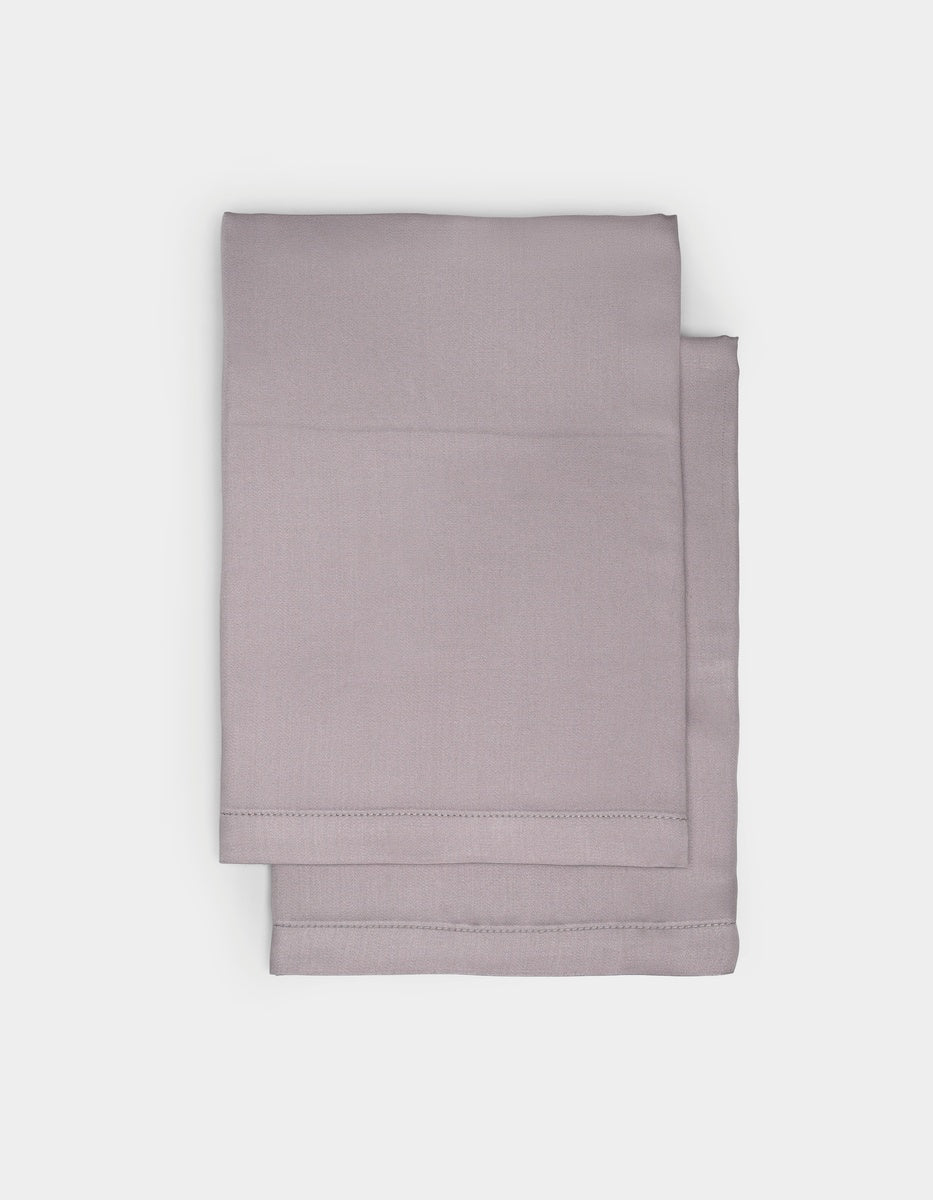 Two neatly folded light gray Cozy Earth Bamboo Pillowcases are stacked on a plain, light background.