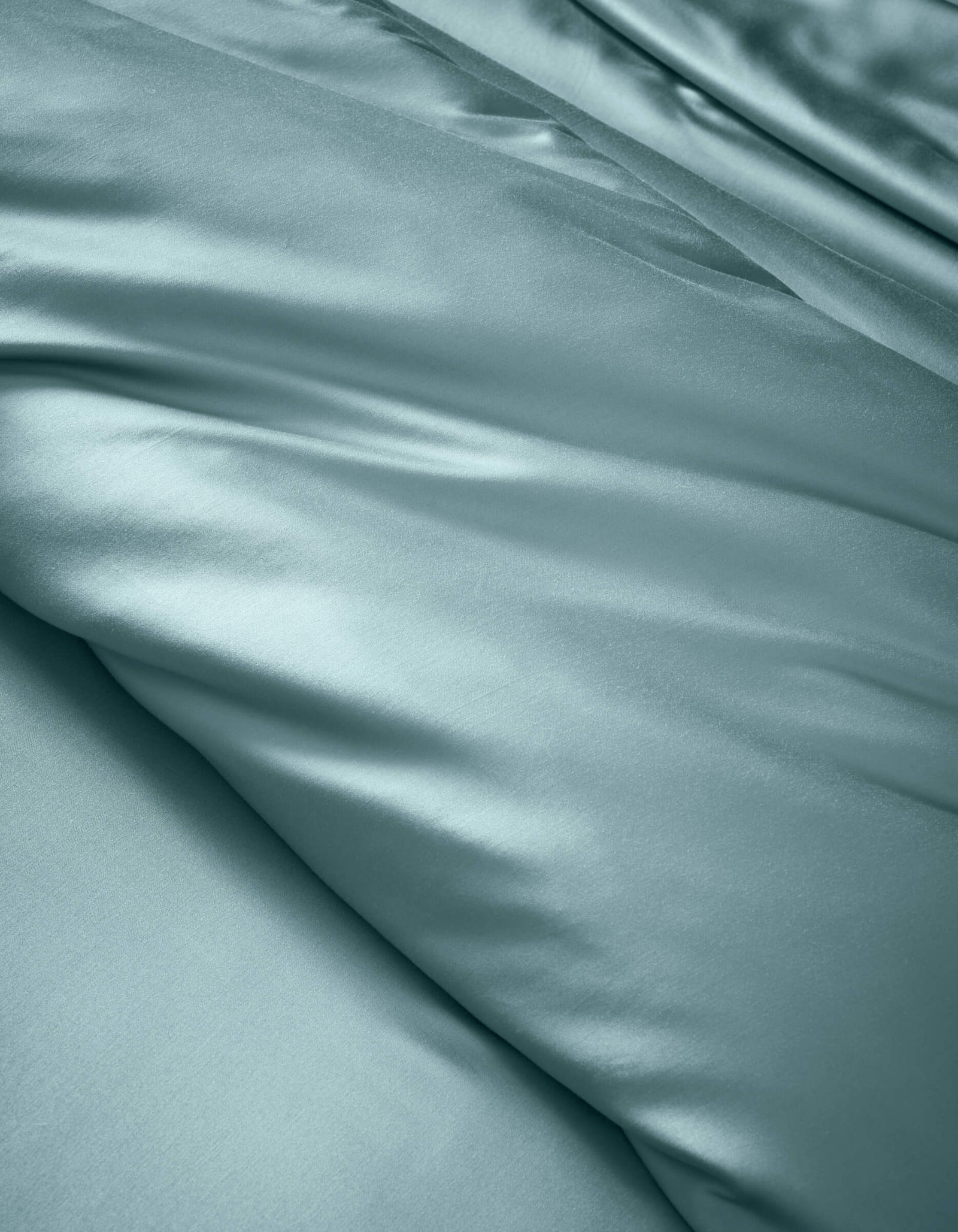 The Cozy Earth Bamboo Duvet Cover features smooth, light blue satin fabric with soft folds and a gentle sheen, offering a luxurious and elegant look.