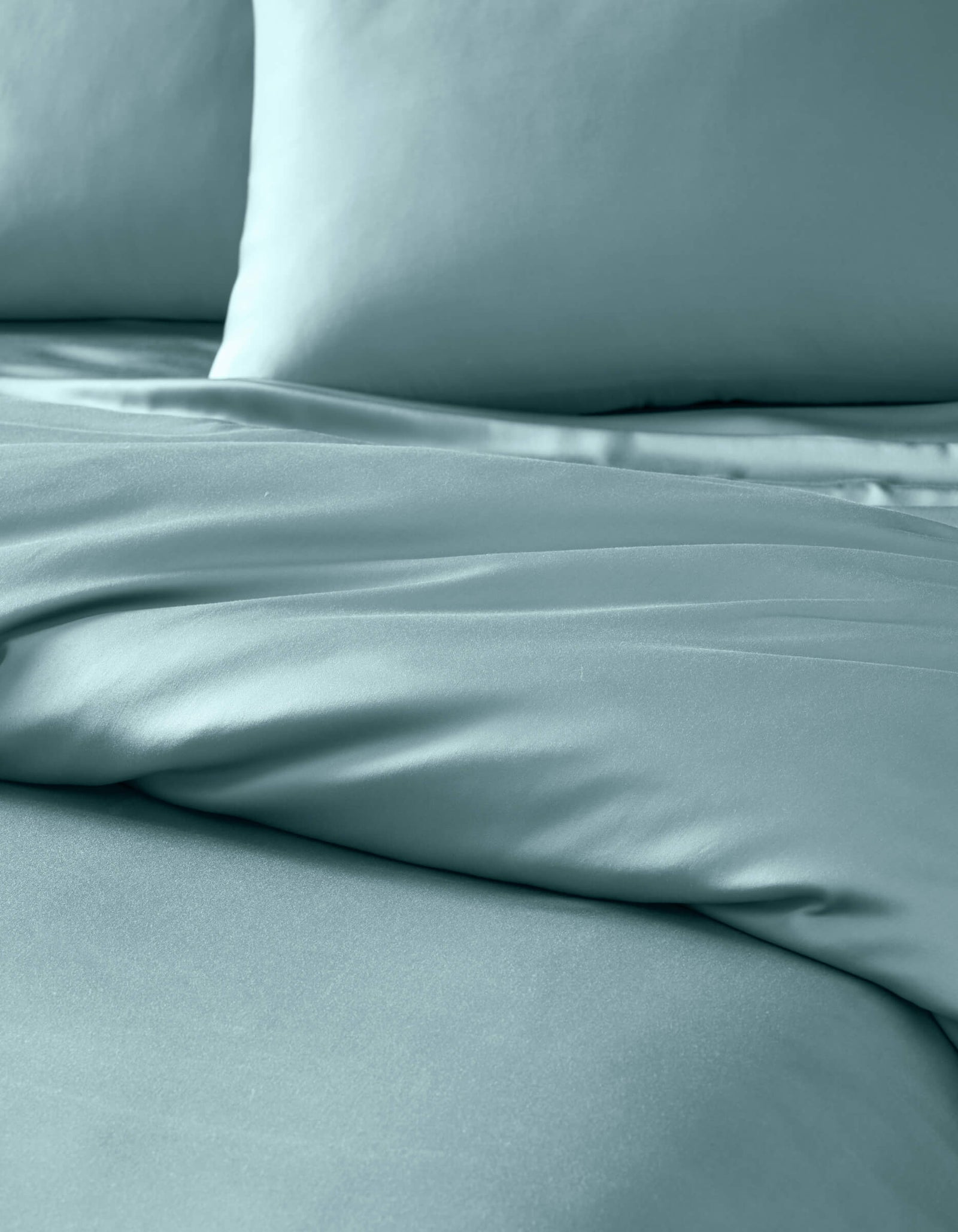 Close-up of a neatly made bed featuring the Cozy Earth Bamboo Duvet Cover in light blue, with two matching pillows. The smooth, soft fabric displays gentle folds for a luxurious look.