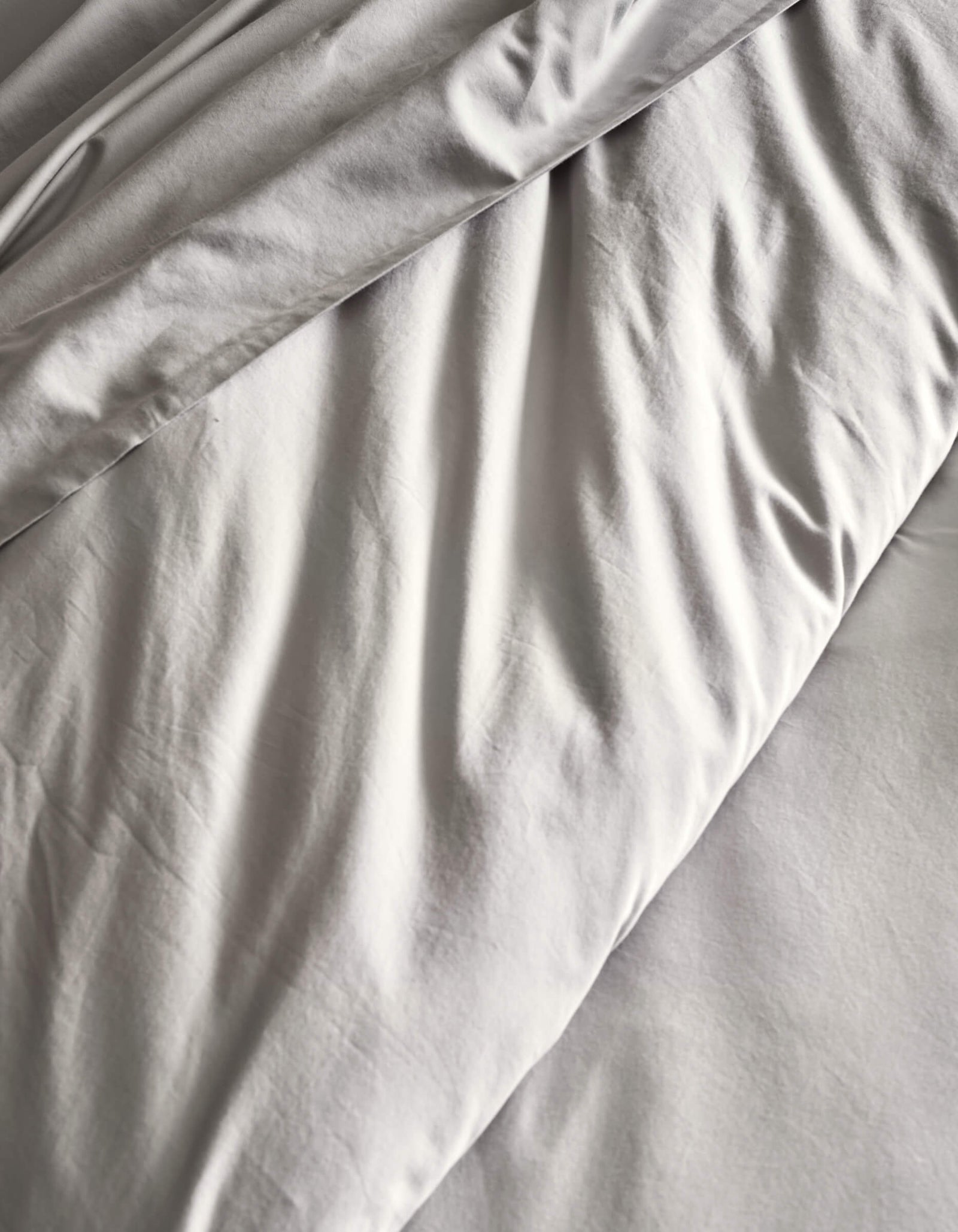 A close-up of the Cozy Earth Soft-Wash Cotton Duvet Set in light gray, featuring gentle folds and creases for a textured, cozy look.
