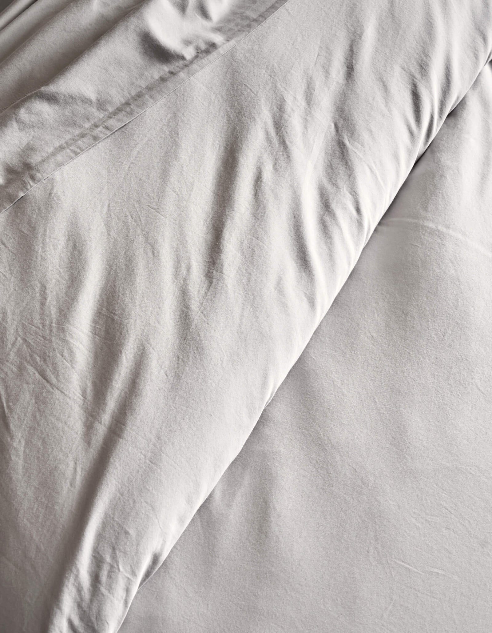 A close-up of a neatly made bed features the Cozy Earth Soft-Wash Cotton Duvet Cover, highlighting its white color and soft folds in the fabric.