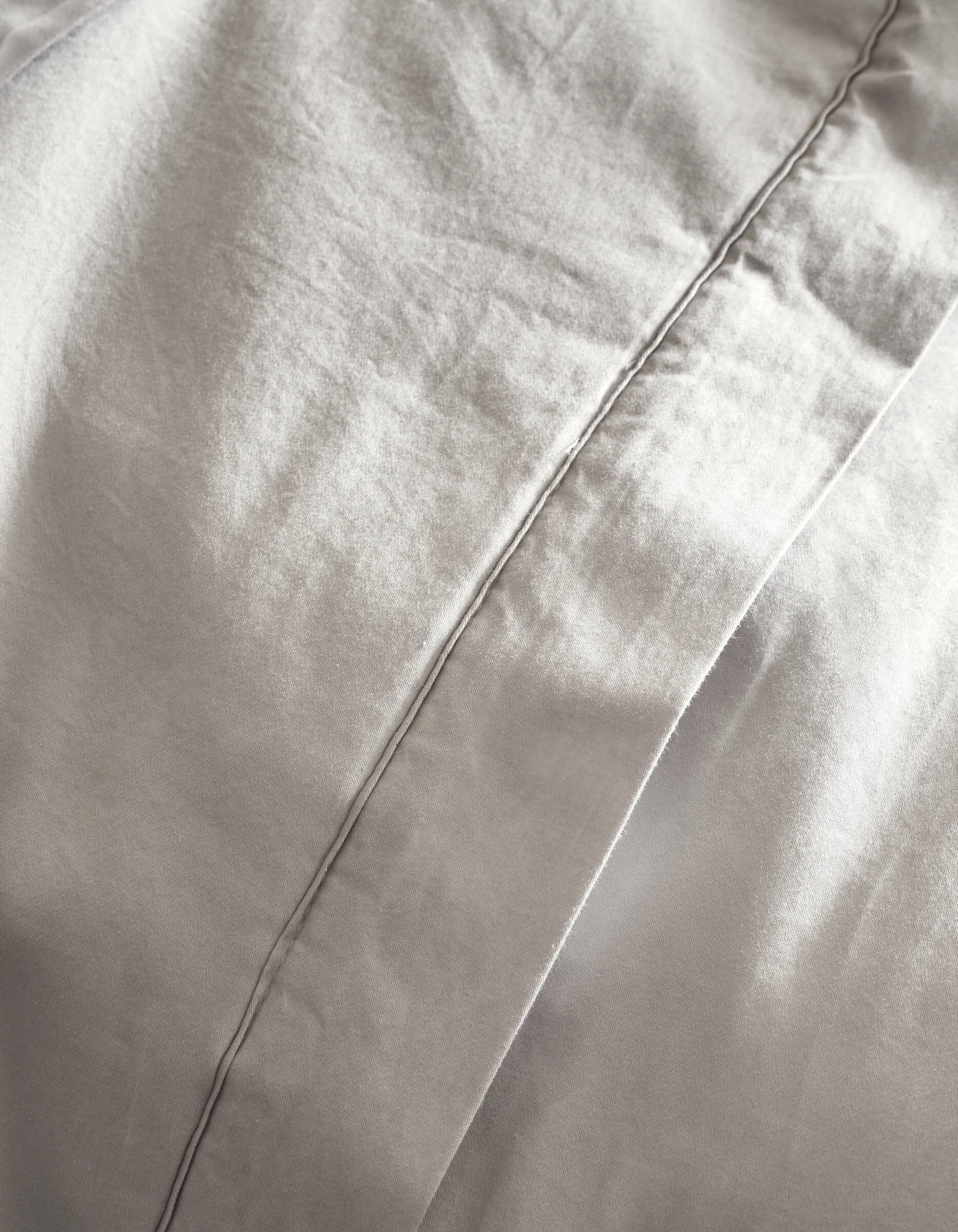 Close-up of Cozy Earth’s Soft-Wash Cotton Quilt in light gray, featuring a prominent vertical stitched seam, gentle folds, and a smooth, soft texture.