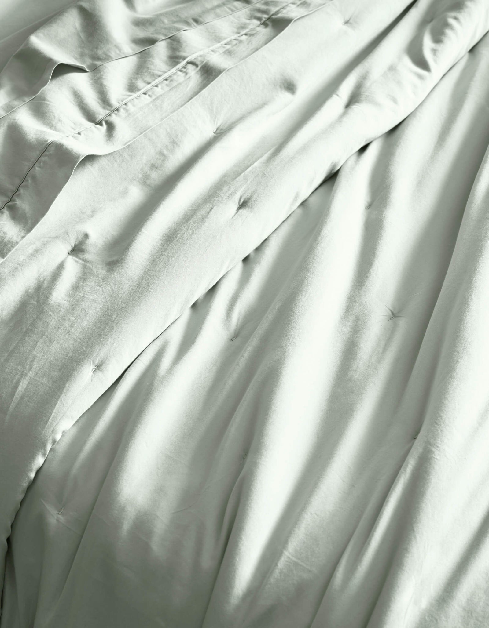 Close-up of Cozy Earth’s Soft-Wash Cotton Quilt, showcasing its light color, gentle folds, and subtle tufted details for a soft, comfortable, and inviting bed.