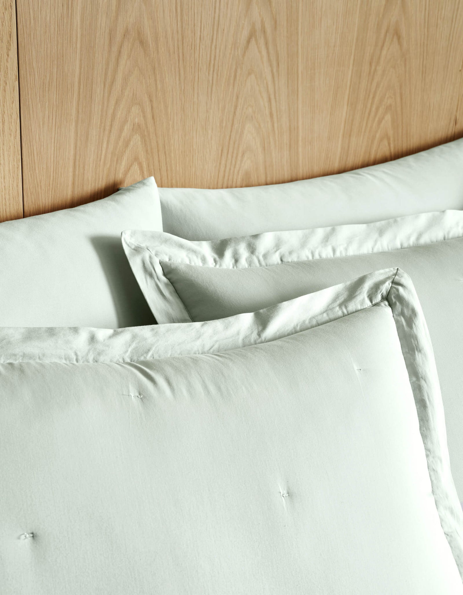 Two Soft-Wash Cotton Quilted Shams by Cozy Earth are neatly arranged against a wooden headboard, creating a clean and minimal bedding setup.