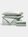 The Cozy Earth Soft-Wash Cotton Bedding Deluxe Bundle, shown neatly folded against a white background, includes two pillows, a duvet cover, and two sheets in light green.|Color:Laurel