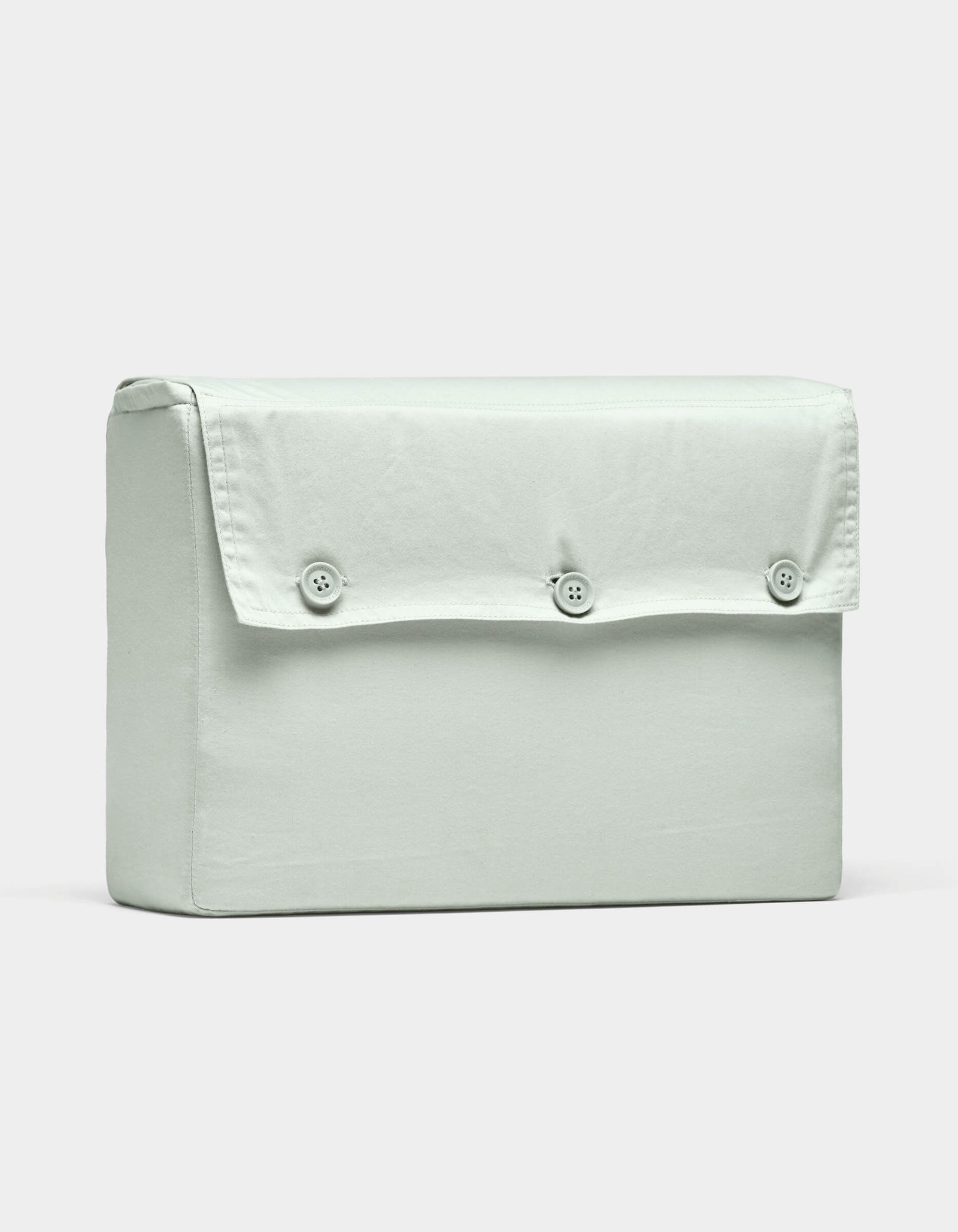 The Soft-Wash Cotton Sheet Set by Cozy Earth is displayed on a plain white background, featuring light grey fabric and a rectangular shape with a flap secured by three buttons.