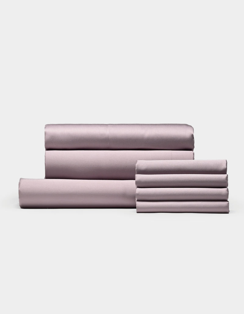 A neatly folded set of Cozy Earth Bamboo Bedding Core Bundle sheets and pillowcases, including both flat and fitted sheets, arranged against a plain white background.