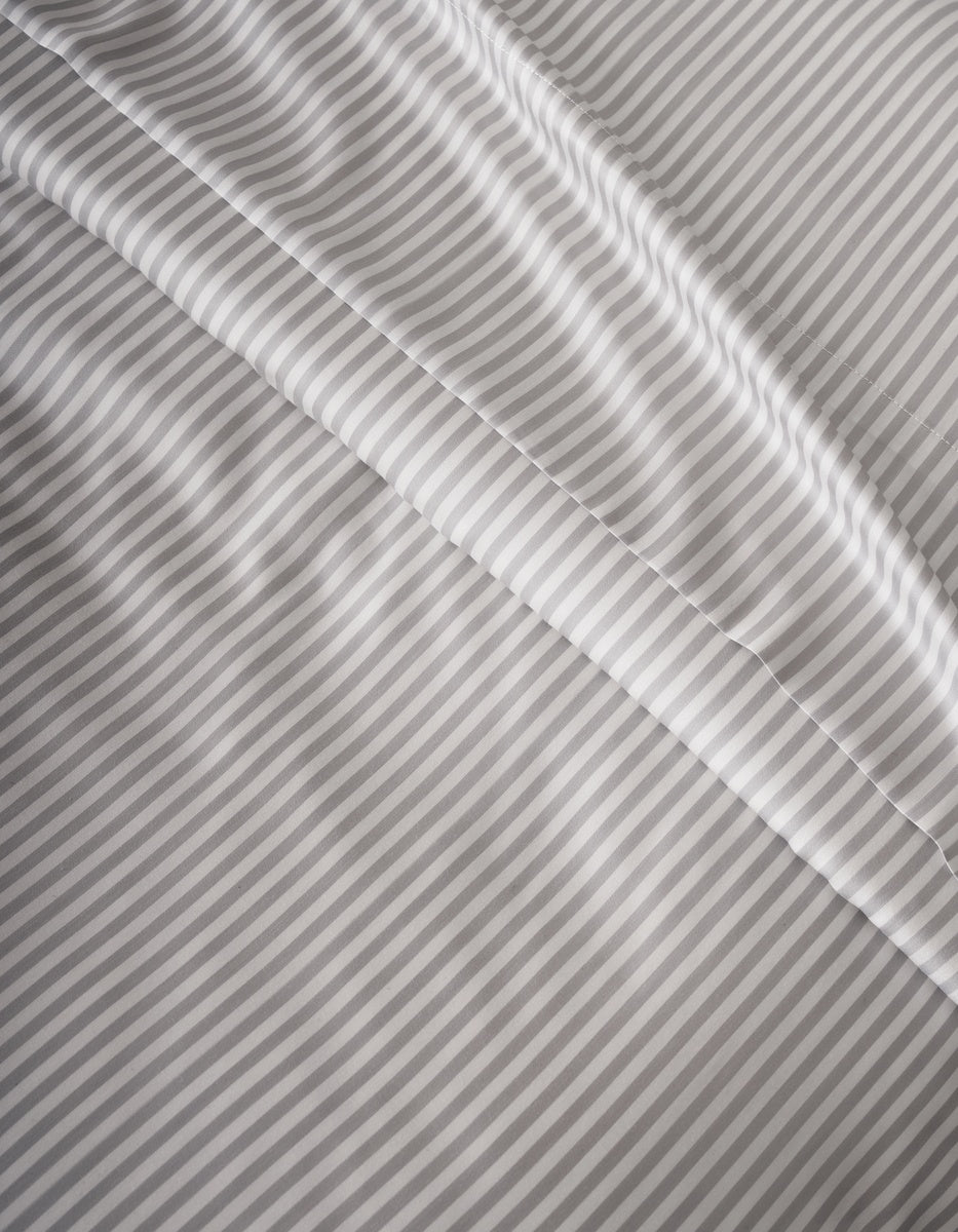 Close-up of Cozy Earth’s Bamboo Duvet Cover in light gray and white stripes, featuring a smooth texture with gentle folds and diagonal lines across the surface.