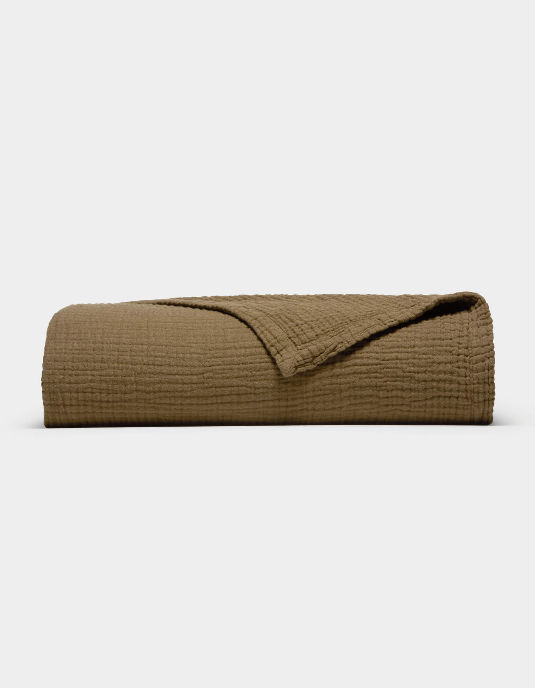 The Cozy Earth Cotton Gauze Blanket, featuring a folded, textured brown design with a corner turned back to reveal its soft inner side, is displayed against a plain white background.|Color:Sable