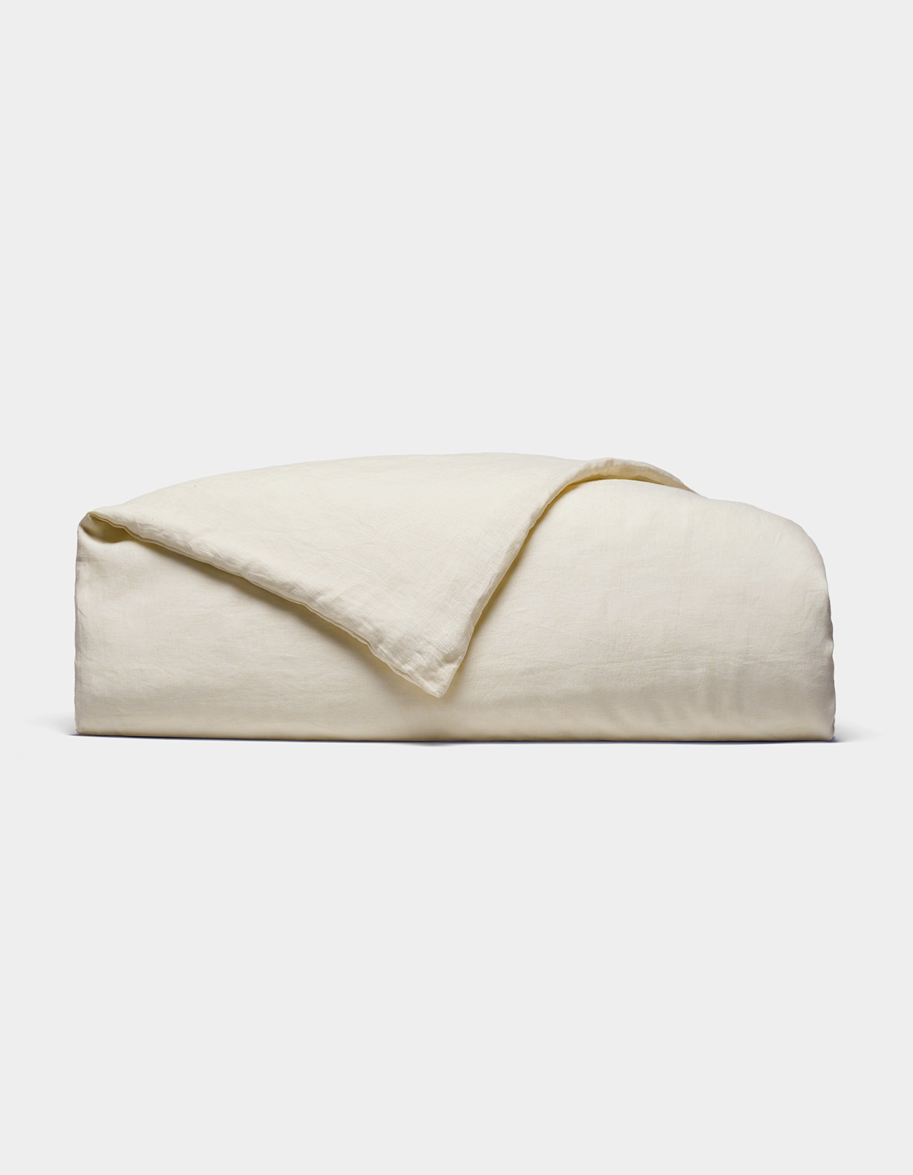 The Cozy Earth Linen Duvet Cover, in an off-white shade, is neatly folded against a white background. Its soft, slightly textured fabric is visible with one corner casually turned over.|Color:Flax