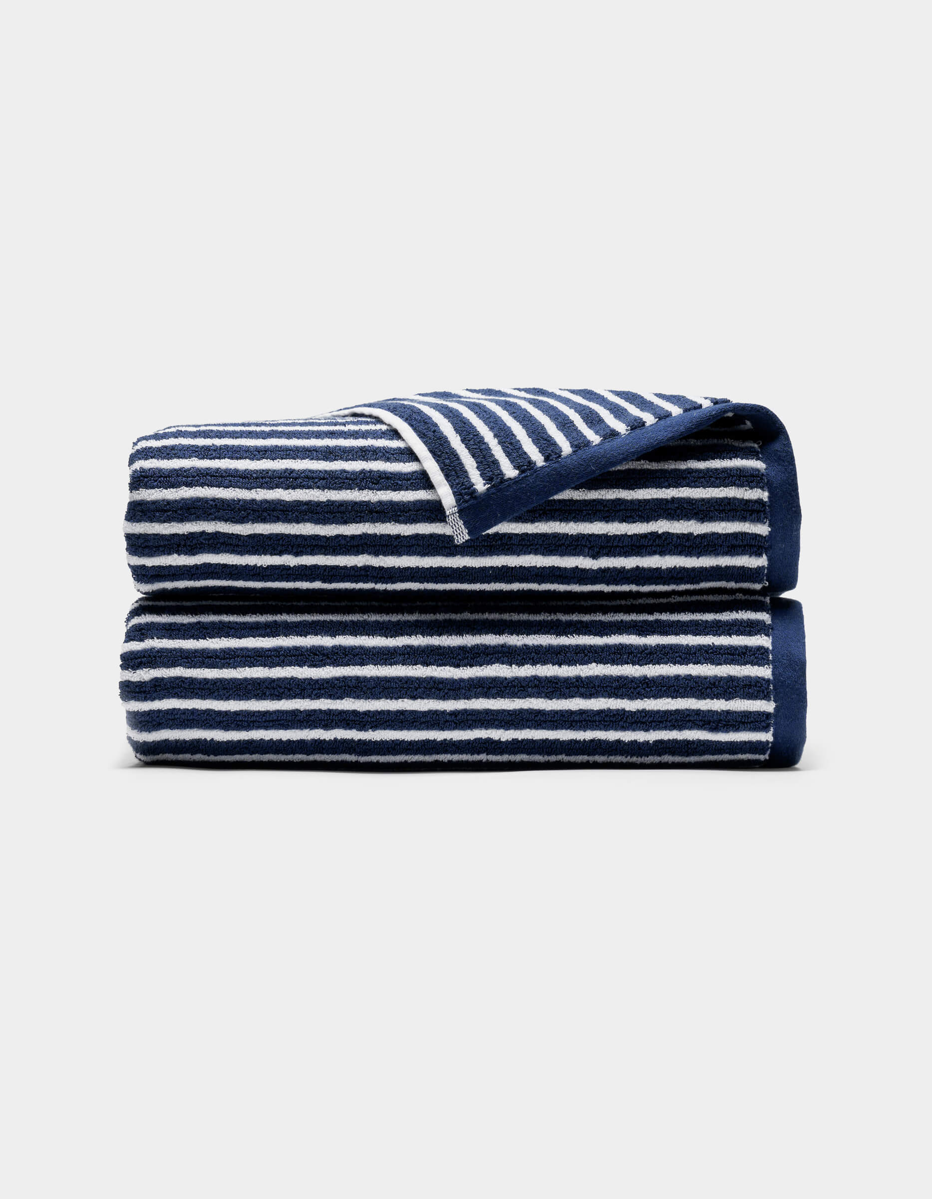 A Ribbed Terry Bath Towel by Cozy Earth, navy blue with white horizontal stripes, is neatly folded and displayed on a light gray background.|Color:Obsidian Stripe