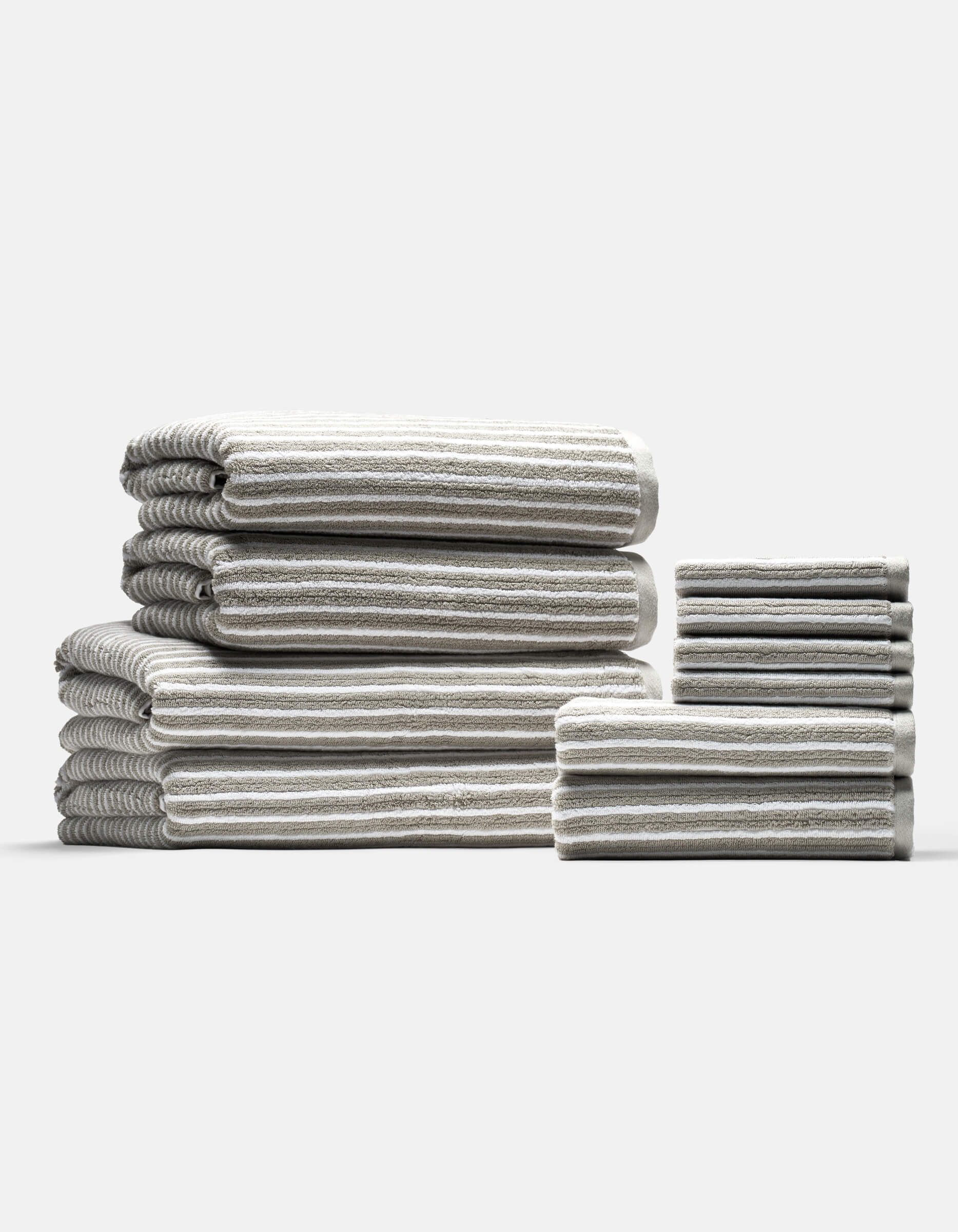 The Cozy Earth Complete Ribbed Terry Bath Bundle features gray and white striped towels in various sizes, neatly folded and arranged into two stacks on a plain light background.|Color:Dew Stripe