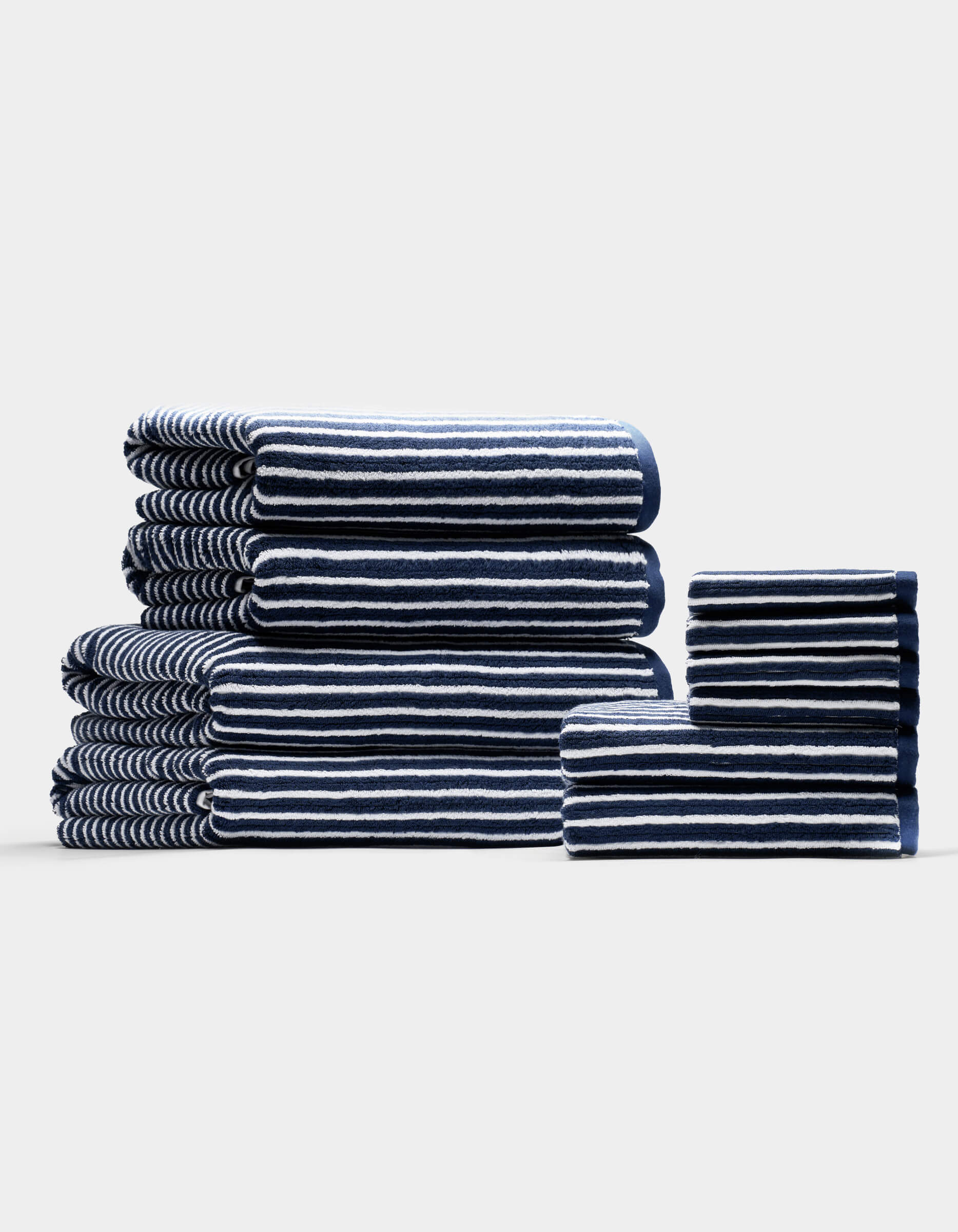 The Complete Ribbed Terry Bath Bundle by Cozy Earth features navy blue towels with white stripes, arranged by size on a plain, light background.