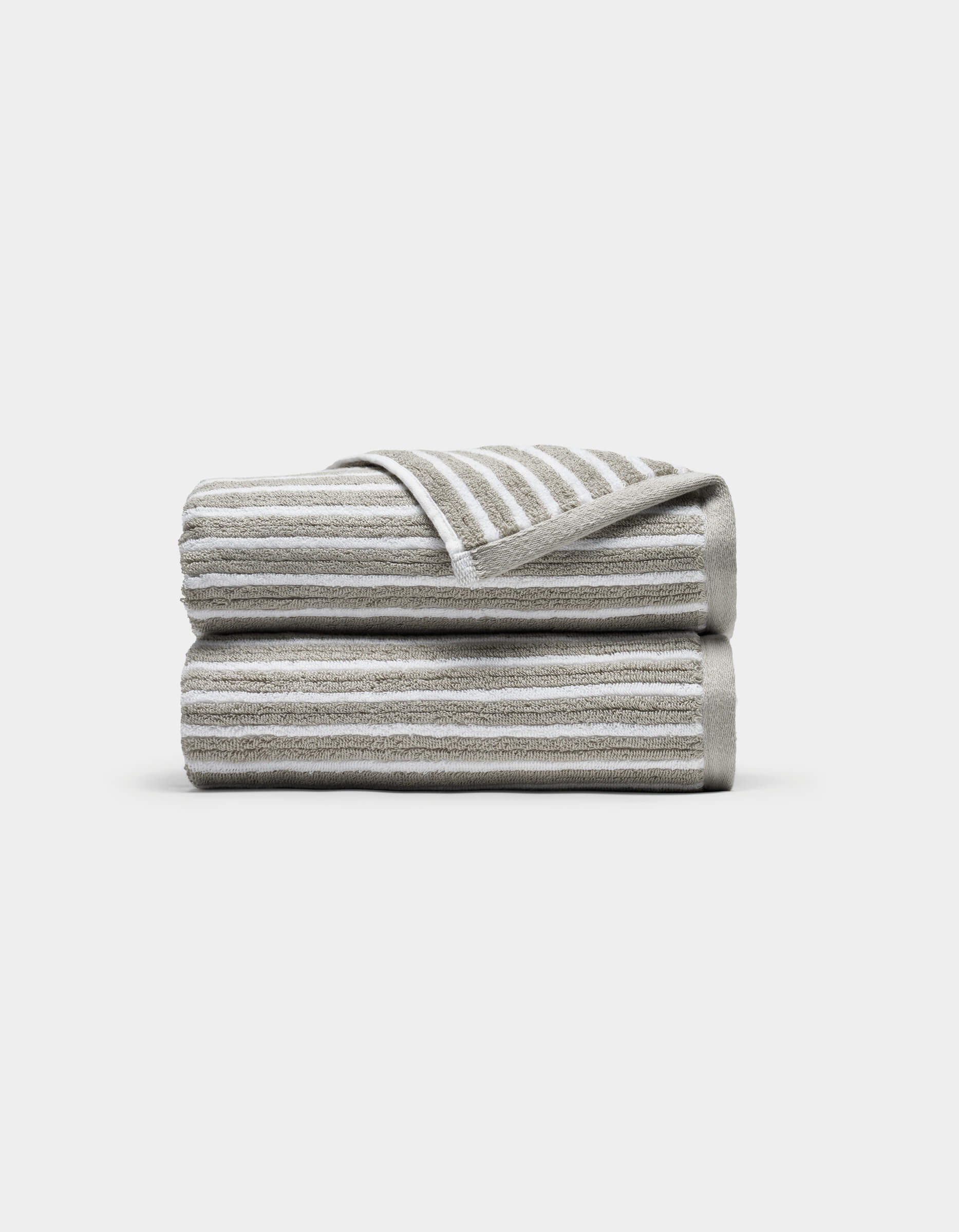 Two Ribbed Terry Hand Towels by Cozy Earth, in beige and white stripes, stacked neatly with one corner of the top towel flipped to show the stripe pattern, set against a plain white background.|Color:Dew Stripe