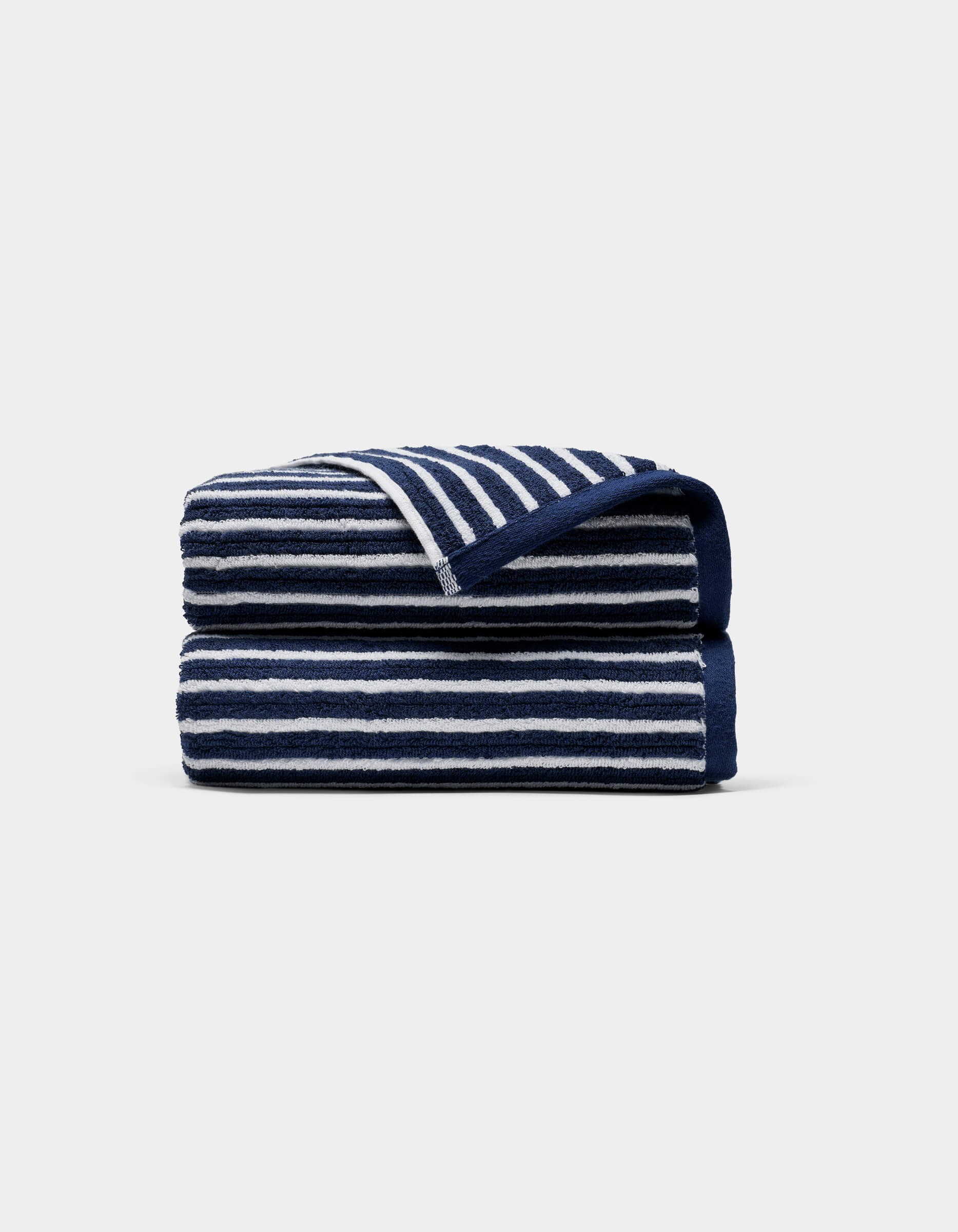 A Ribbed Terry Hand Towel by Cozy Earth, featuring horizontal navy blue and white stripes, is neatly folded against a plain light gray background.