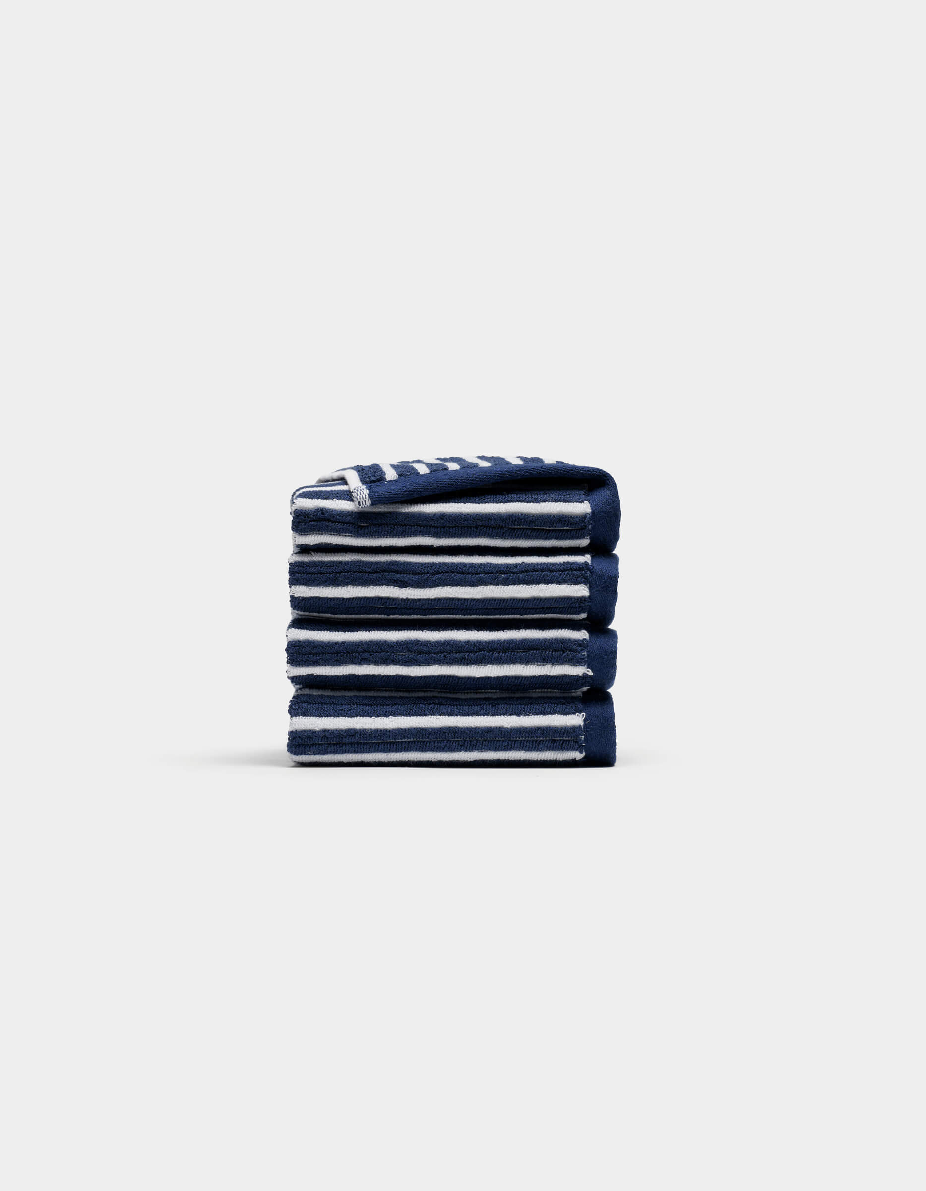 A neatly folded stack of four Cozy Earth Ribbed Terry Washcloths in navy blue and white stripes is centered on a plain, light gray background.